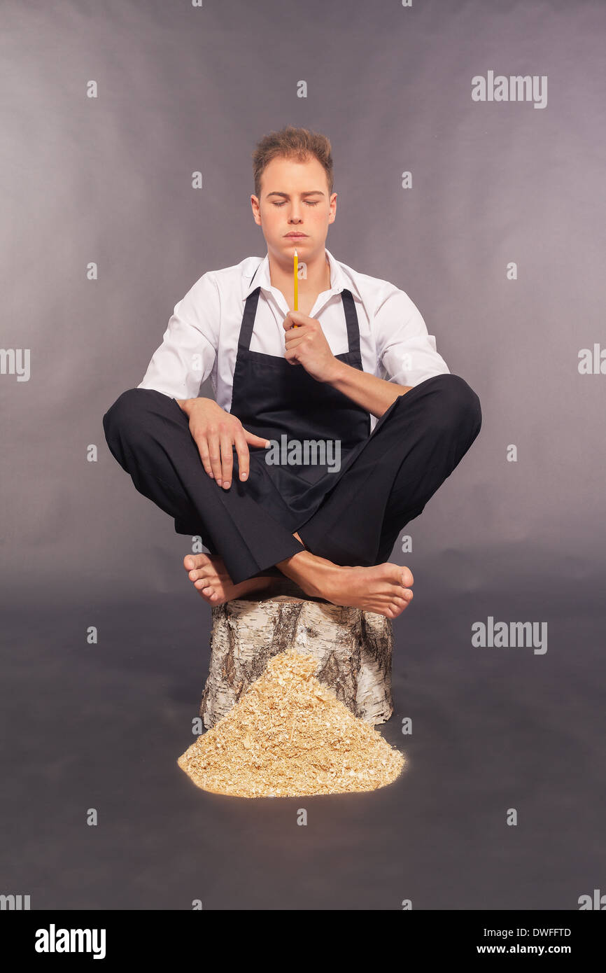 Thoughtful man in dungarees chipping wood Stock Photo