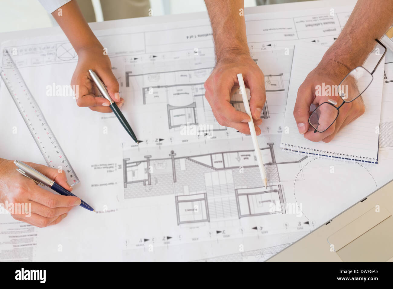 Several hands working on blueprints Stock Photo