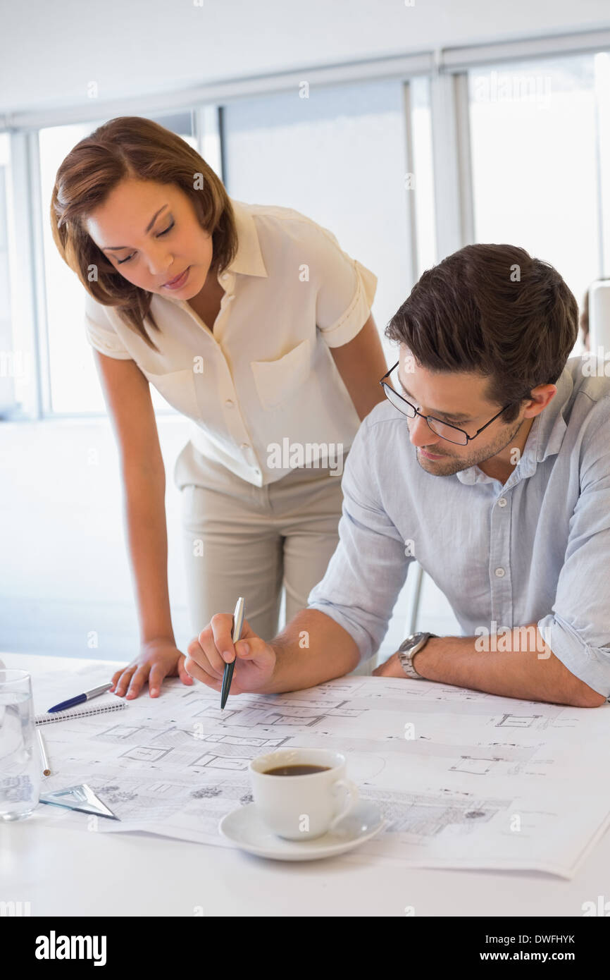 Concentrated colleagues working on blueprints at office Stock Photo
