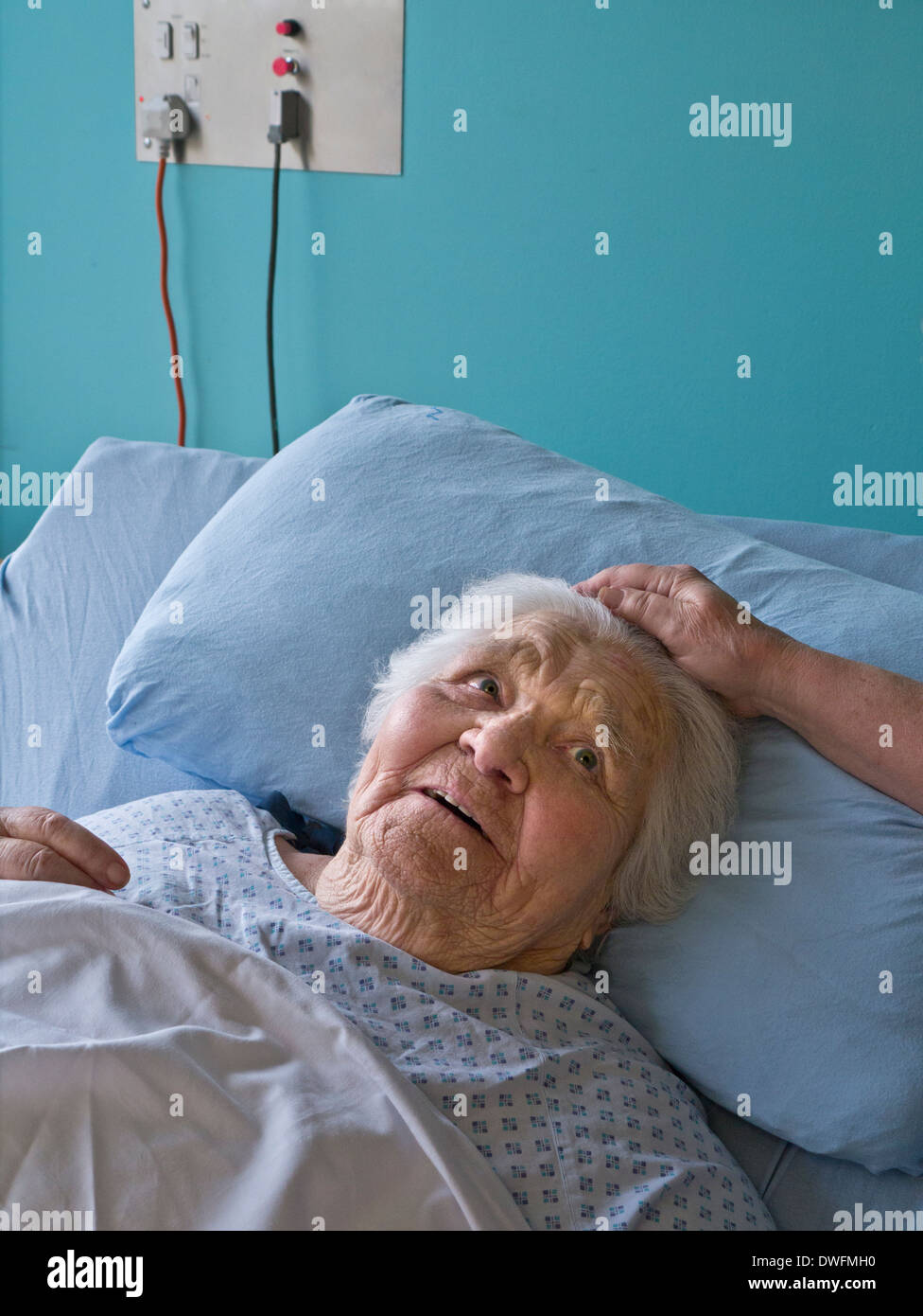Elderly old lady hospital care bed contented & cared for, secure smiling senior old age woman with comforting touching hand of visiting carer nurse Stock Photo