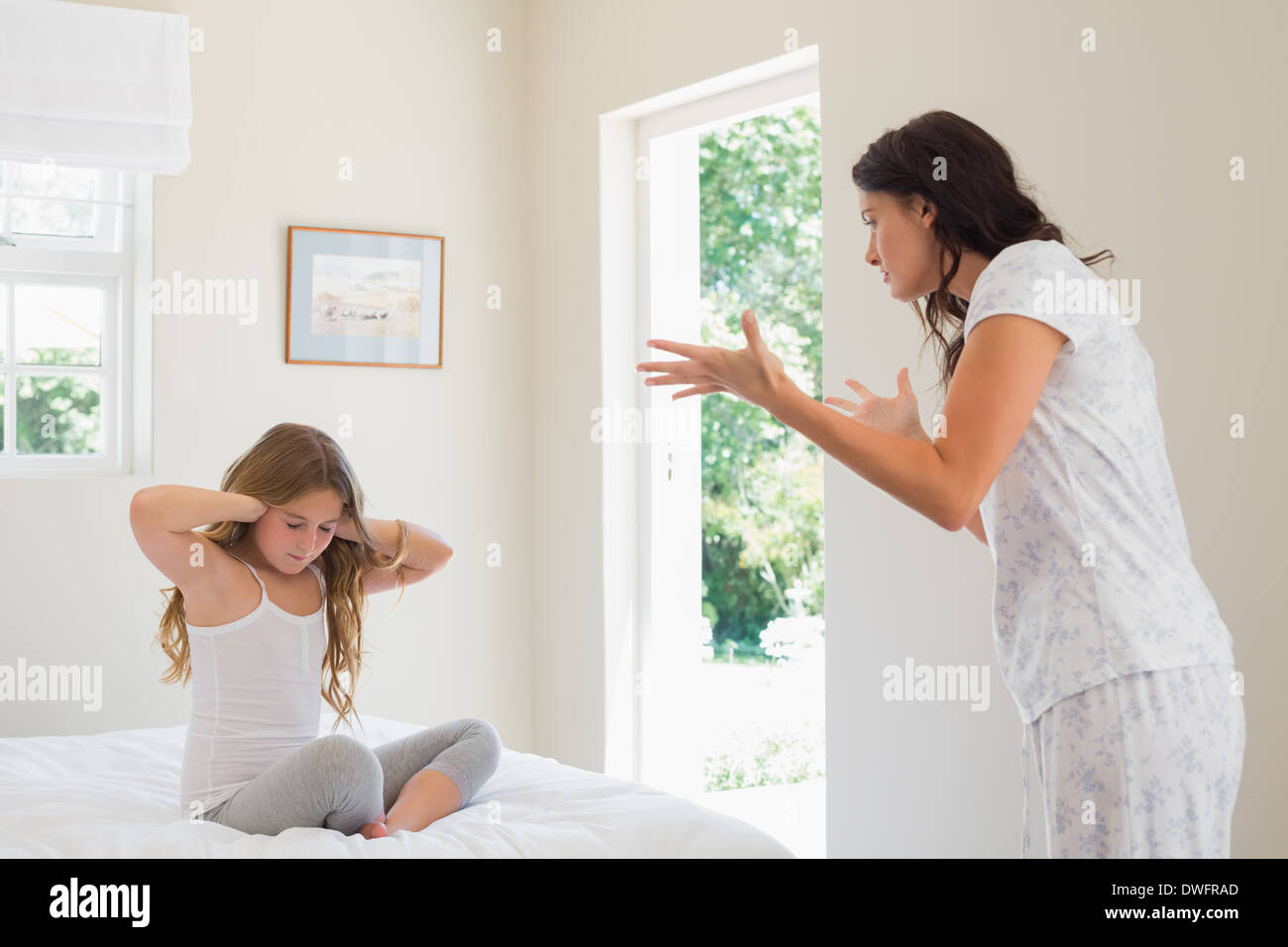 Girl covering ears while mother scolding bedroom Stock Photo Alamy