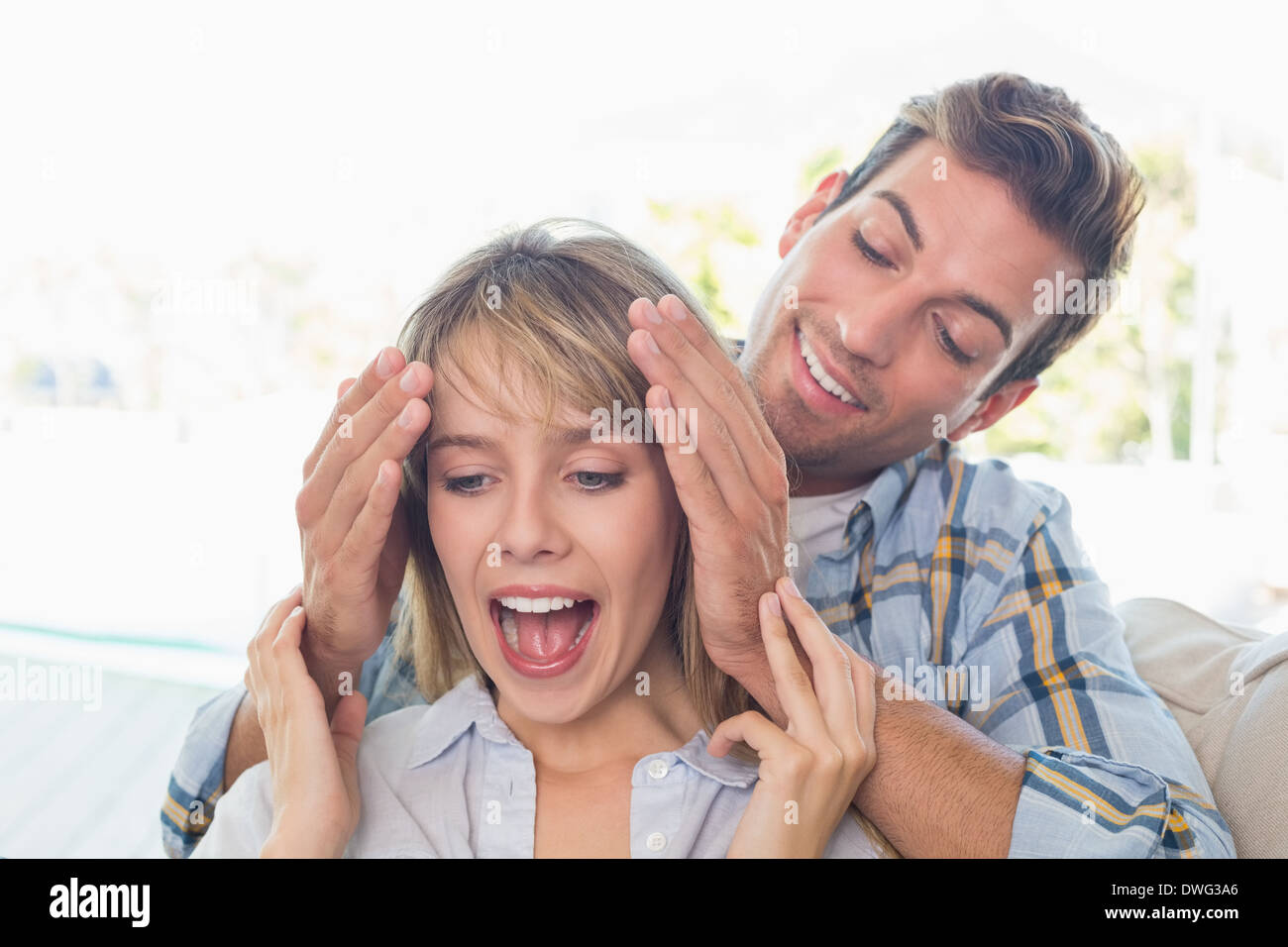 Man surprising woman in living room Stock Photo - Alamy