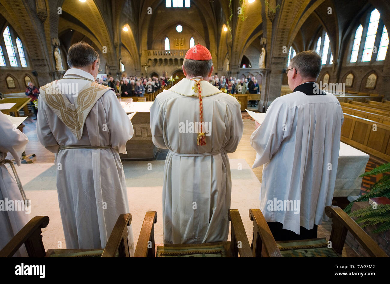 A priest, a cardinal (red cap) and their helpers are standing during a mass in the roman catholic 'Onze lieve Vrouwekerk' church Stock Photo