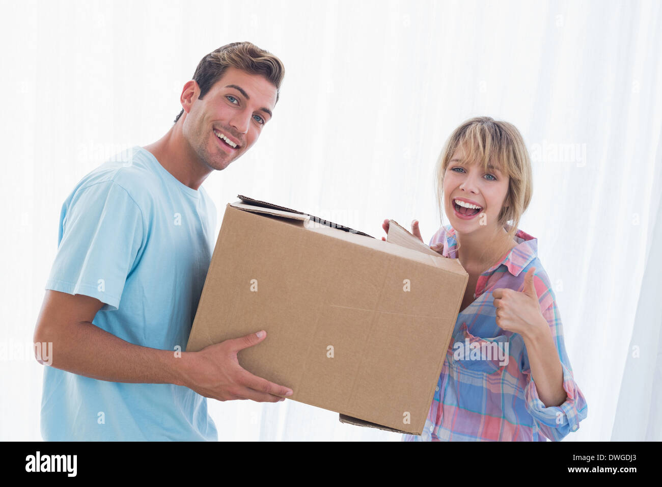 Happy couple carrying cardboard box in new house Stock Photo - Alamy