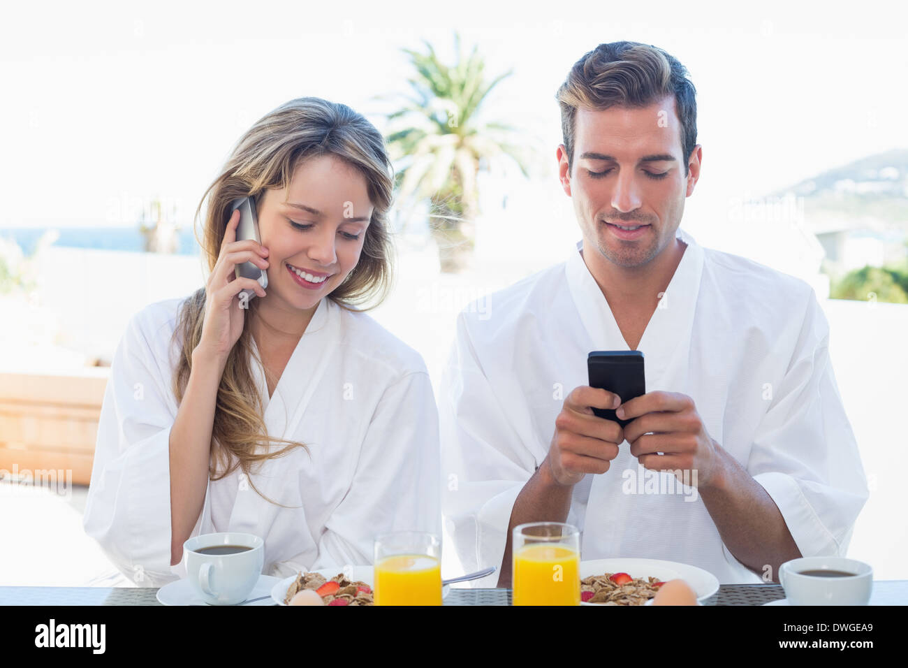 Couple using mobile phones while having breakfast Stock Photo