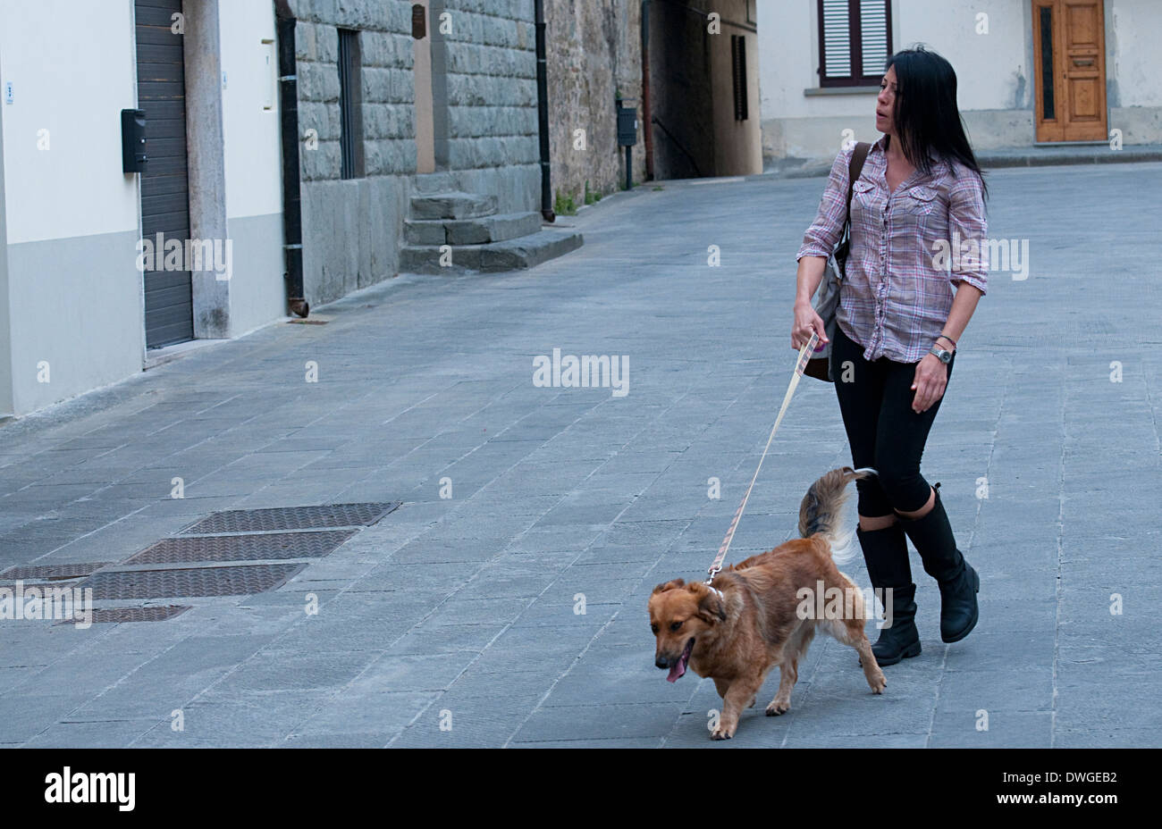 A young woman and her dog strolling through a deserted square in Lastra a Signa, Florence, Tuscany, Italy, Europe Stock Photo