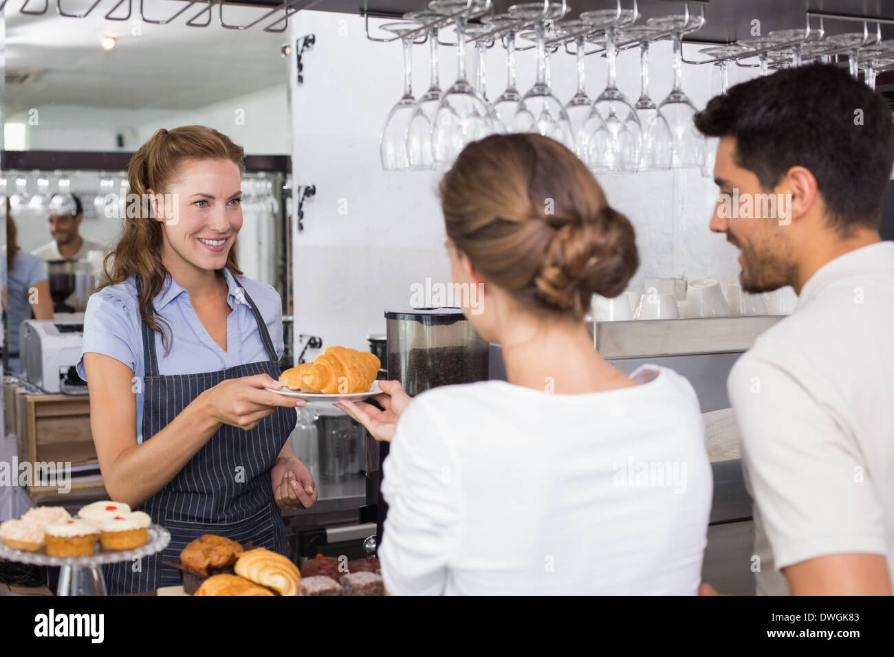 Waiter giving sweet food to a couple at coffee shop Stock Photo