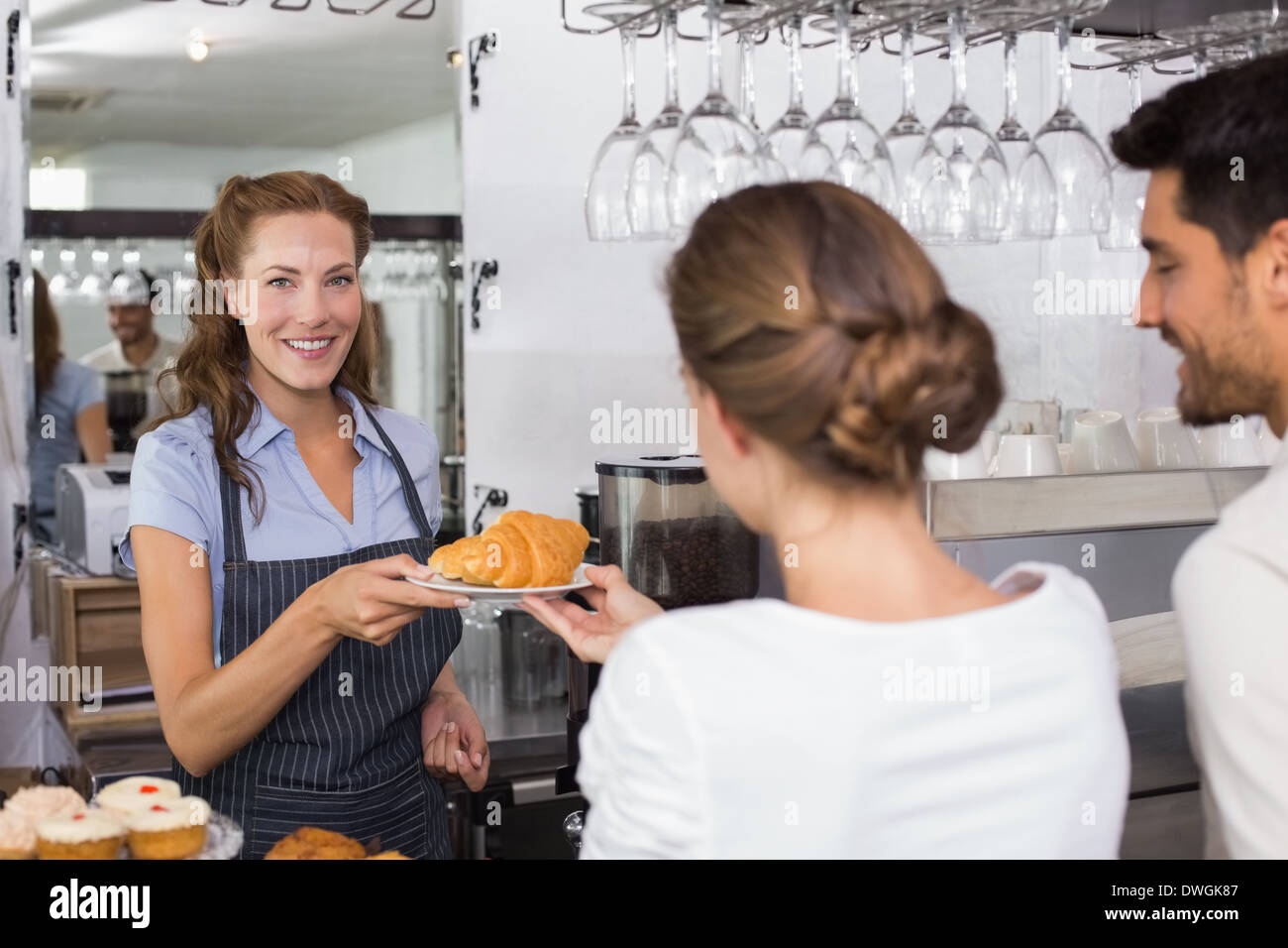 Waiter giving sweet food to a couple at coffee shop Stock Photo