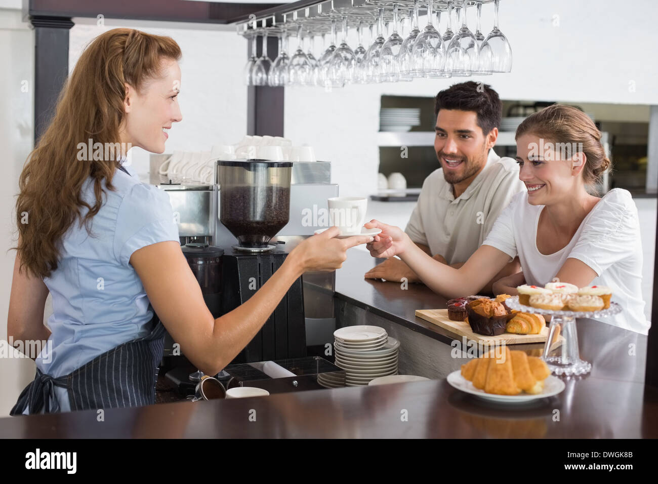 Female waiter giving coffee to a couple at coffee shop Stock Photo