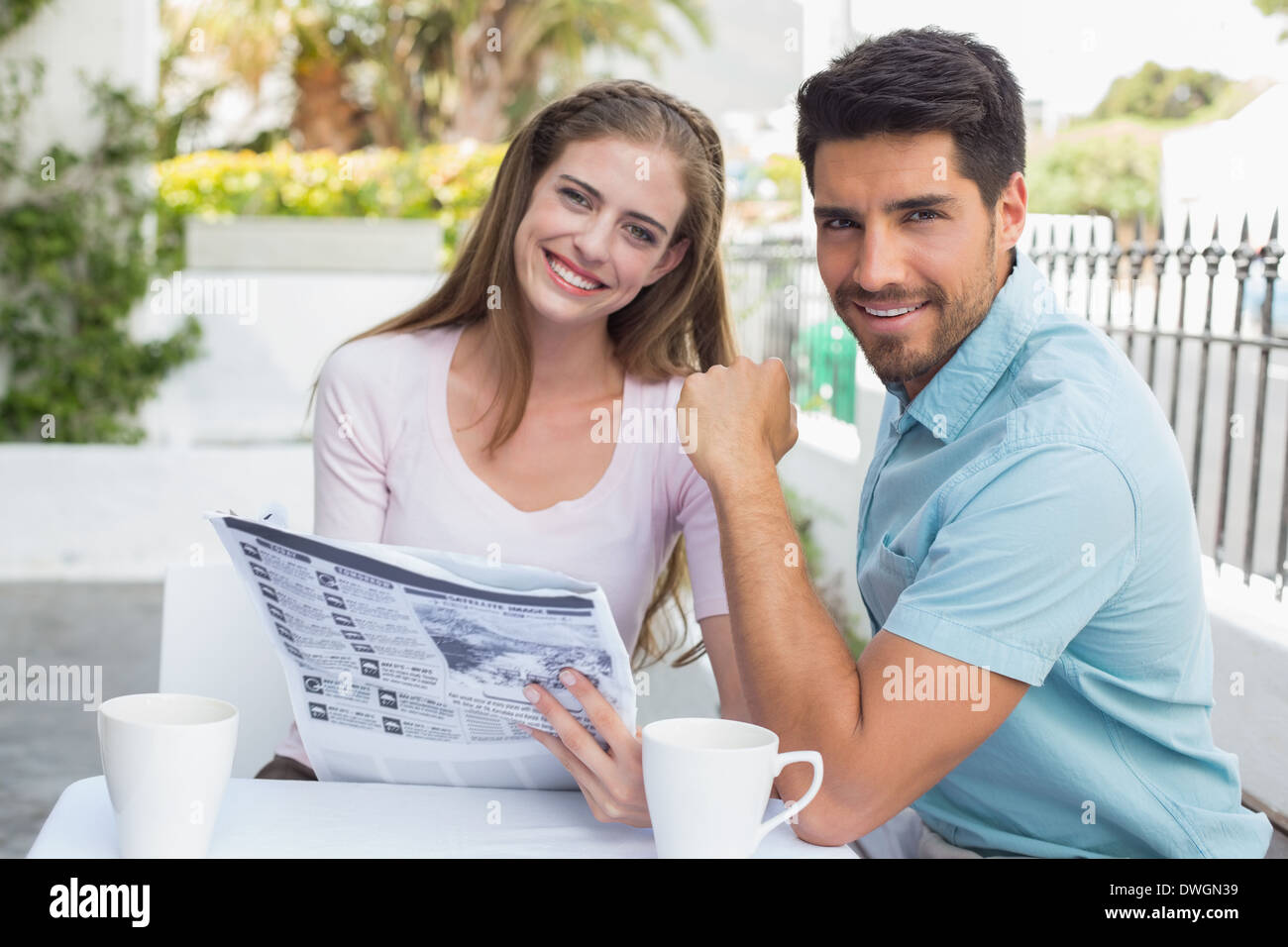 Smiling couple reading newspaper at caf├⌐ Stock Photo