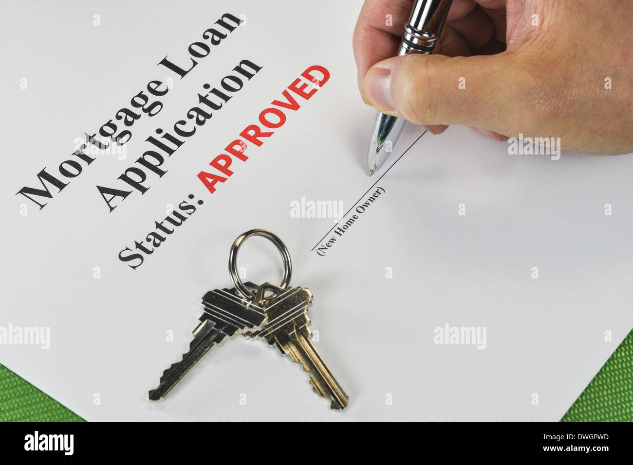 Hand Signing An Approved Real Estate Mortgage Loan Document With House Keys Stock Photo