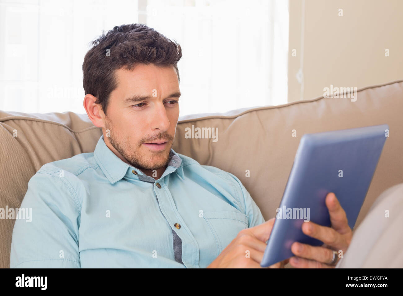 Relaxed man using digital tablet on couch Stock Photo