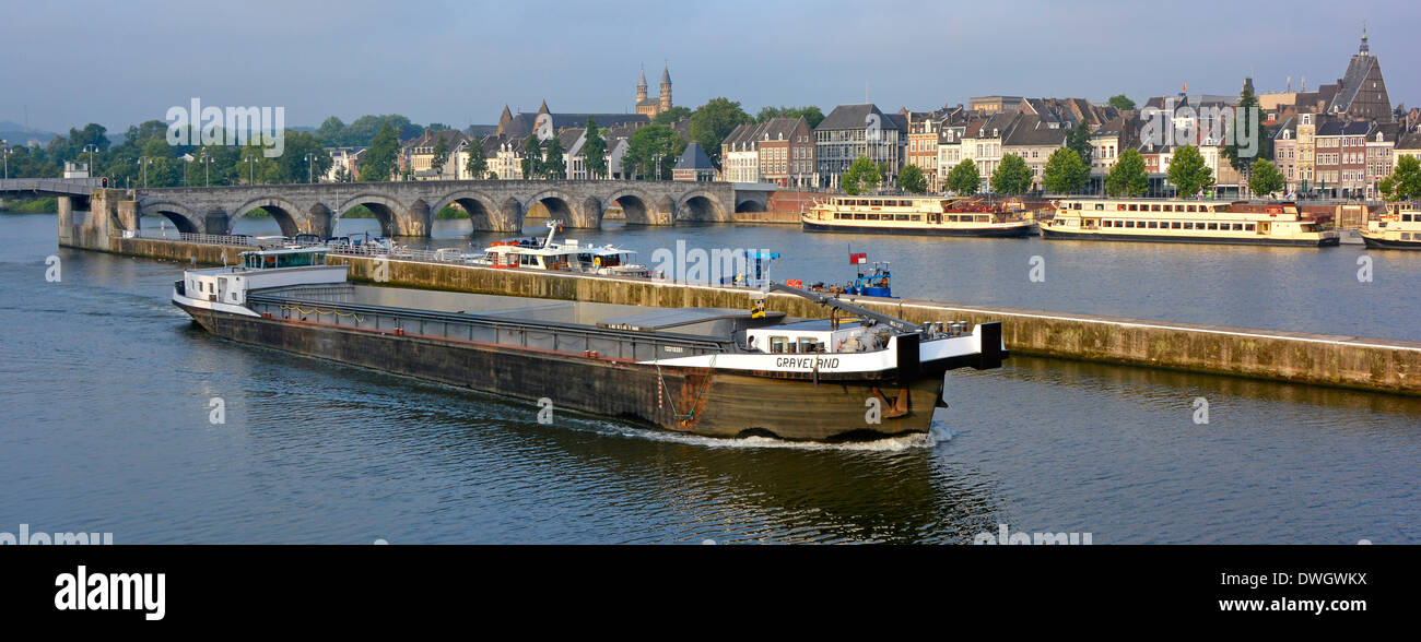 Maastricht commercial transport on River Meuse (River Maas) motor barge travels along dedicated channel passing urban landscape & tour boat moorings Stock Photo