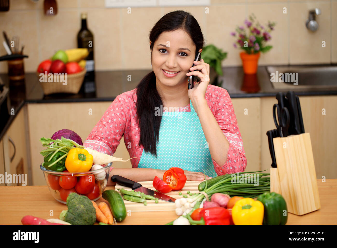 Young Indian woman working with tablet and talking on cellphone Stock Photo