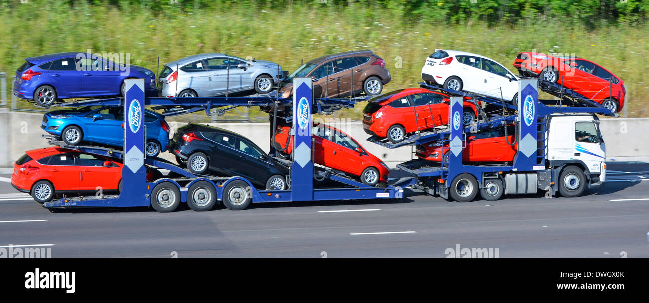 Car transporter supply chain transport hgv truck lorry & trailer loaded with eleven colourful load of new Ford cars on m25 motorway Essex England UK Stock Photo