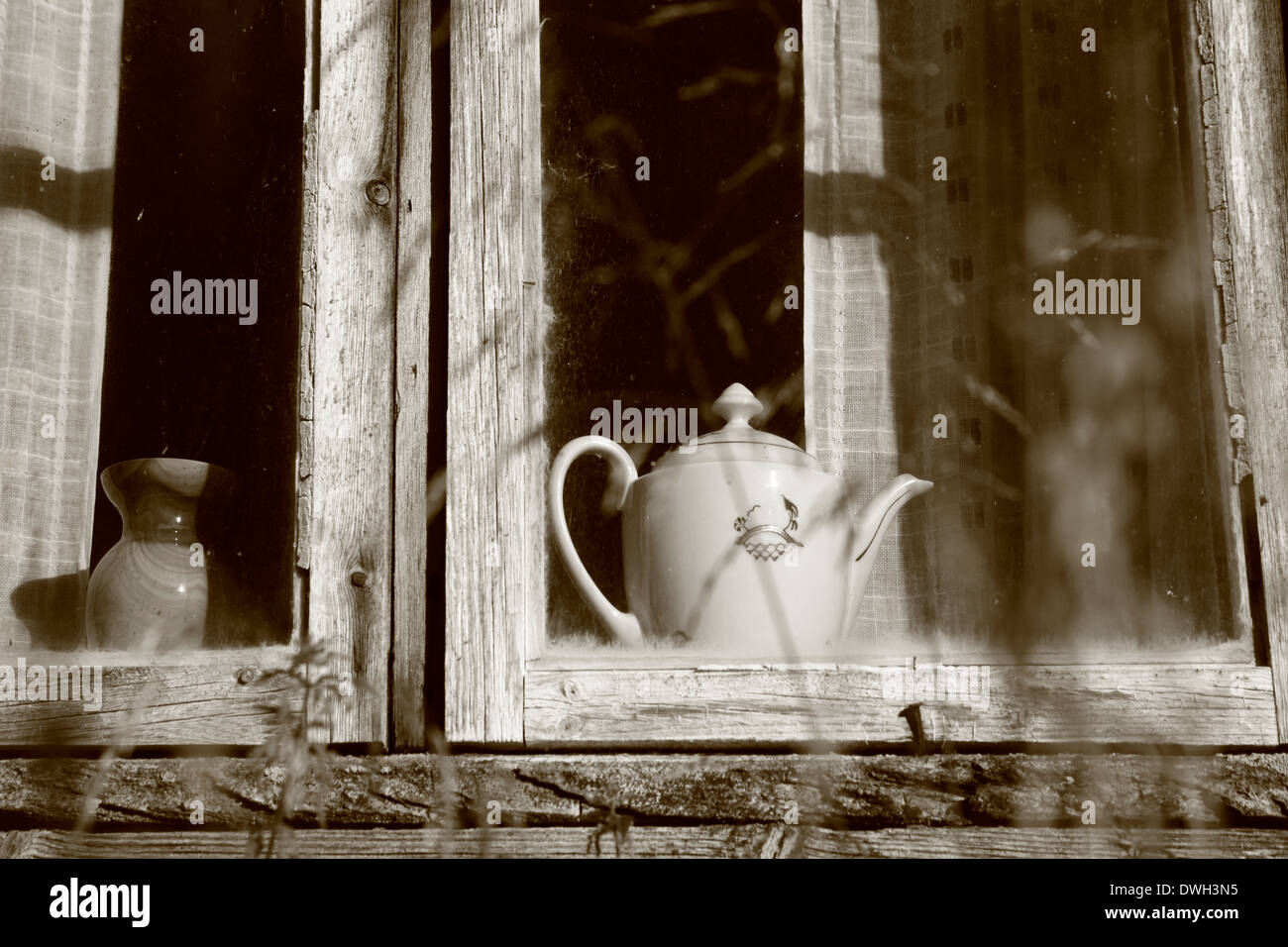 Coffee pot in the window of an old log-house. Black and white photograph, tinted sepia. Stock Photo