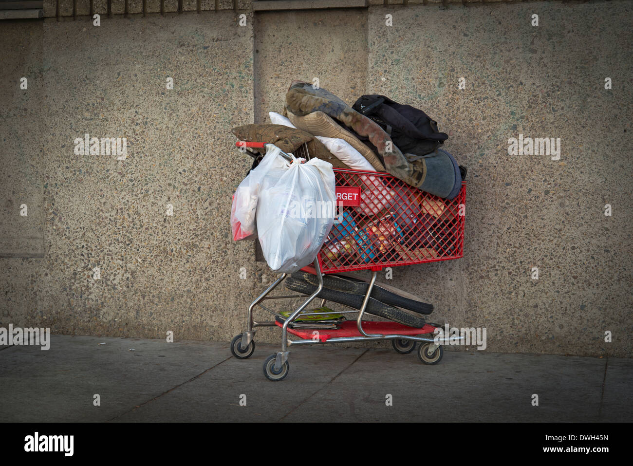 Belongings of homeless individual in shopping cart left on sidewalk, East Village, Downtown San Diego, California Stock Photo