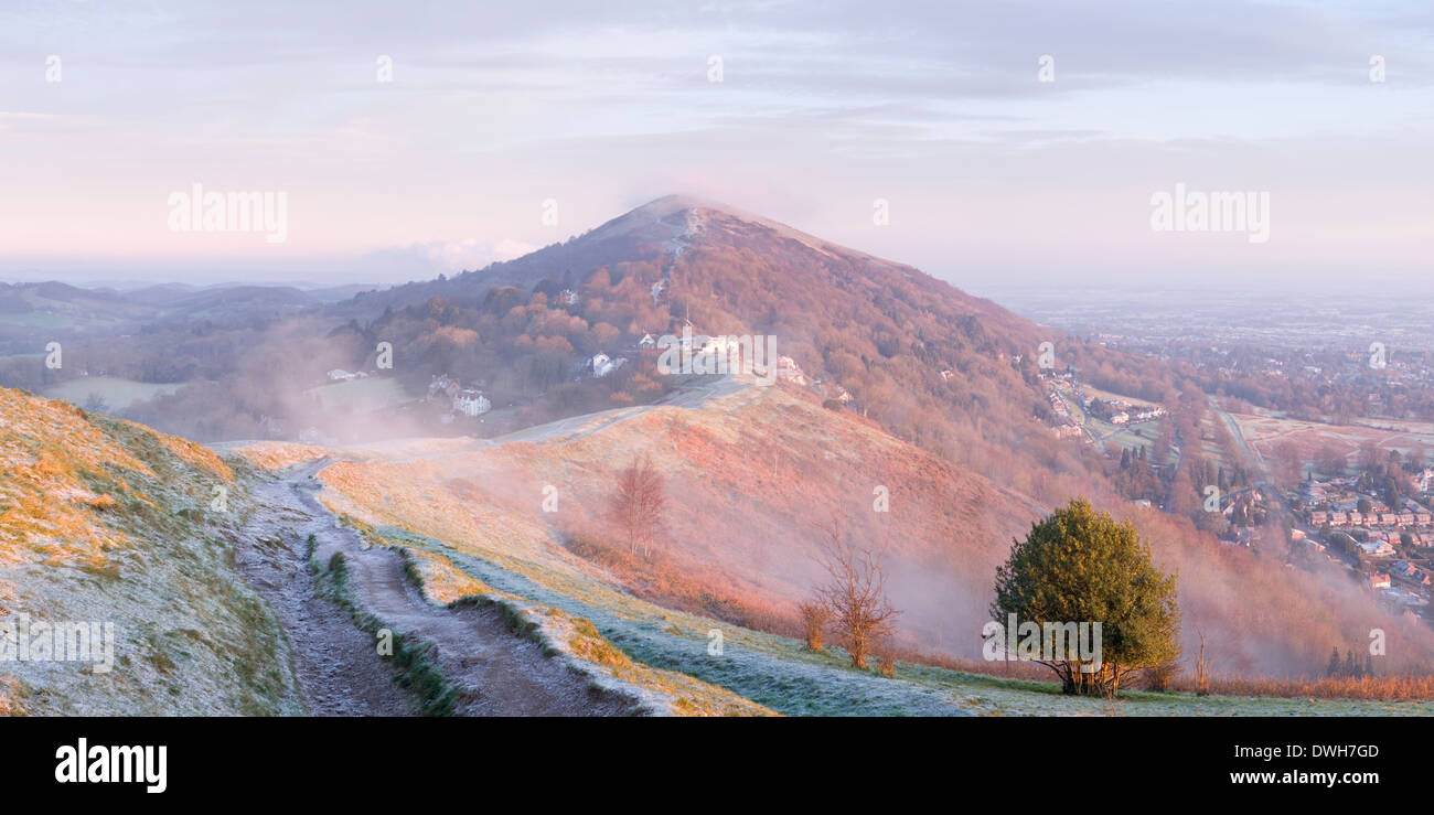 A heavily worn footpath on Perseverance Hill, Malvern Hills, is cast in shadow from the strong light of sunrise. Stock Photo