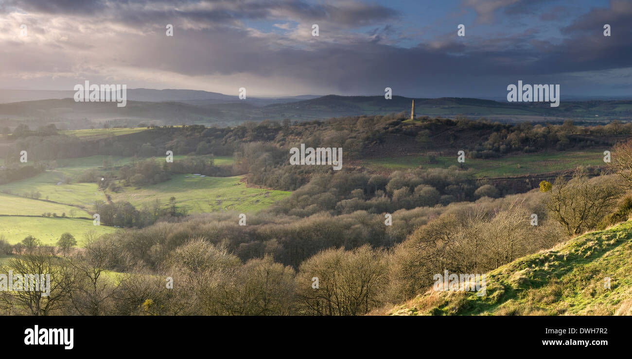 The strong side-lighting of sunset lights up the countryside of Herefordshire and the Eastnor Obelisk from Midsummer Hill. Stock Photo
