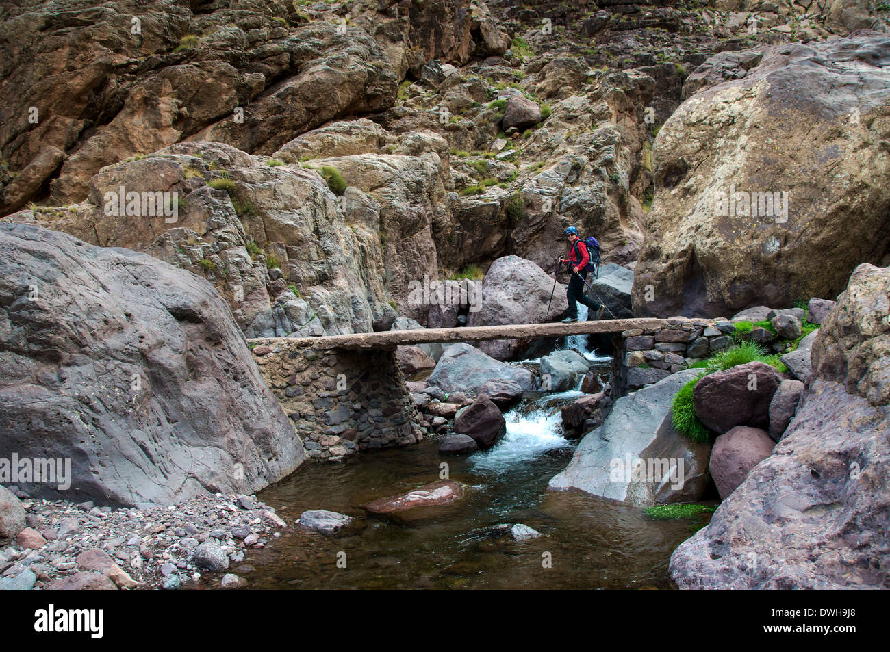 A trekker crossing a bridge on the trek from Toubkal back to the village of Imlil in Morocco Stock Photo