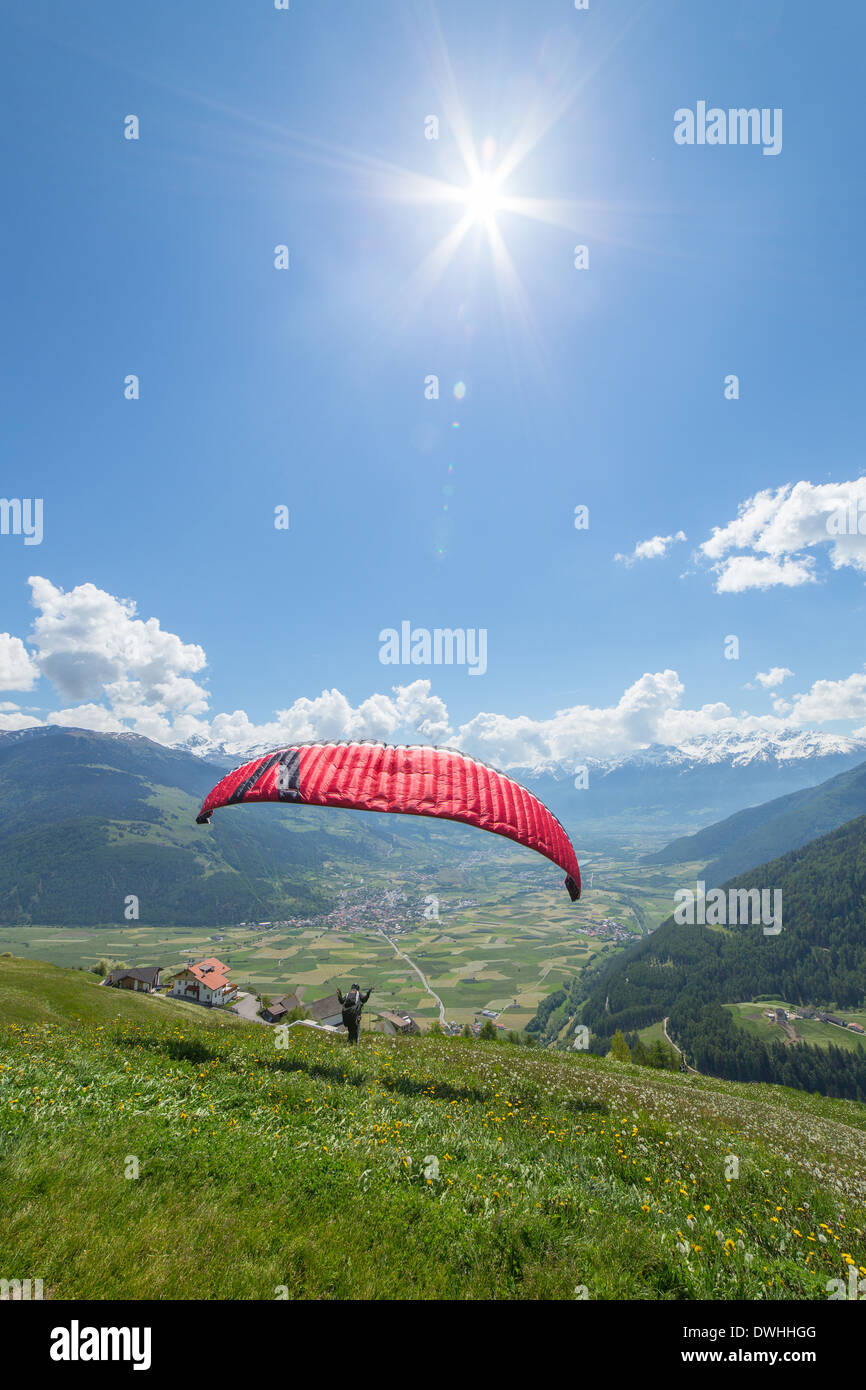Paraglider starts in the italian alps on a green meadow Stock Photo