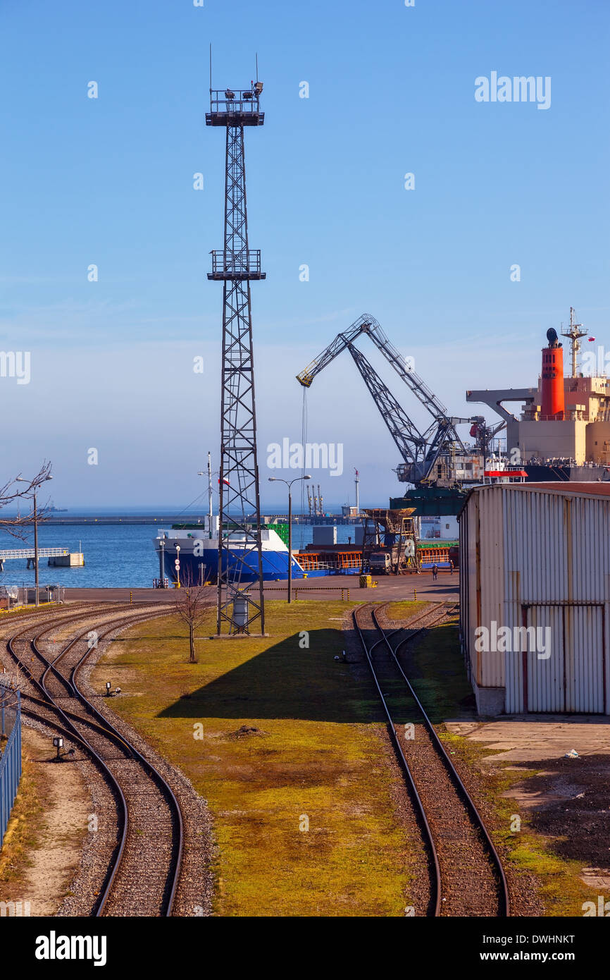 Railroad tracks by a port, with ship loading cargo Stock Photo - Alamy