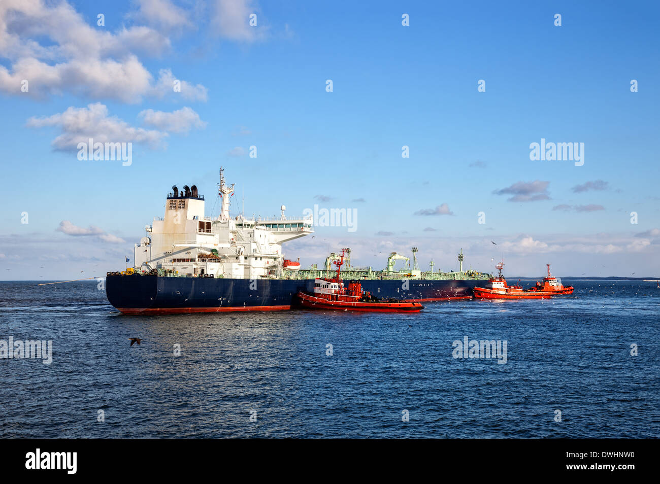 A huge oil tanker and three tugboats at work. Stock Photo