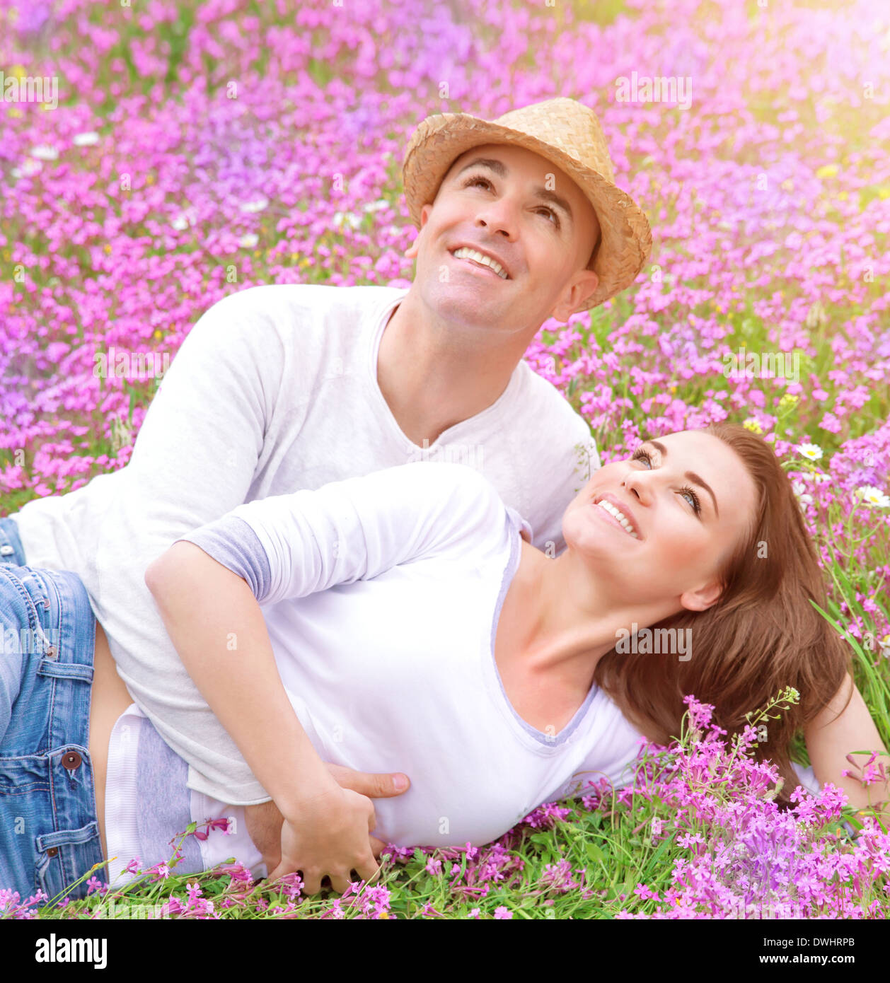 Happy family in spring park lying down on flowers meadow and looking up ...