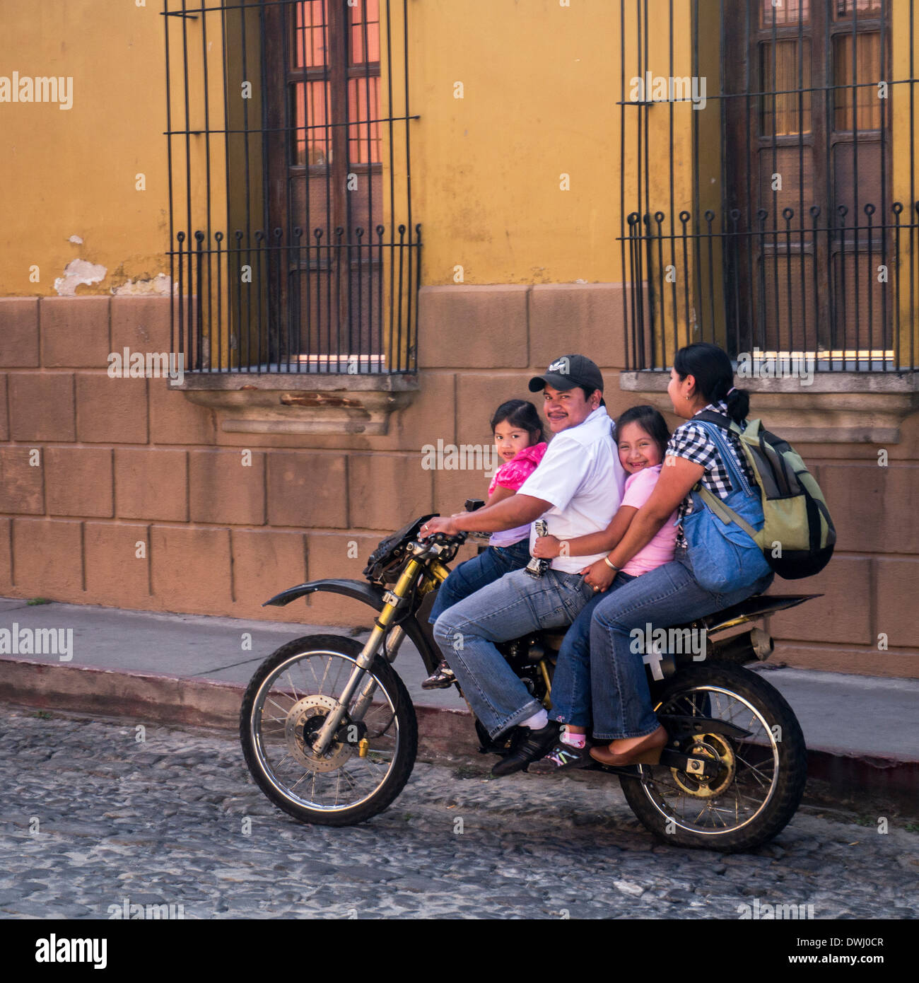 Guatemalan family rides a moped in the cobbled streets of Antigua Guatemala Stock Photo