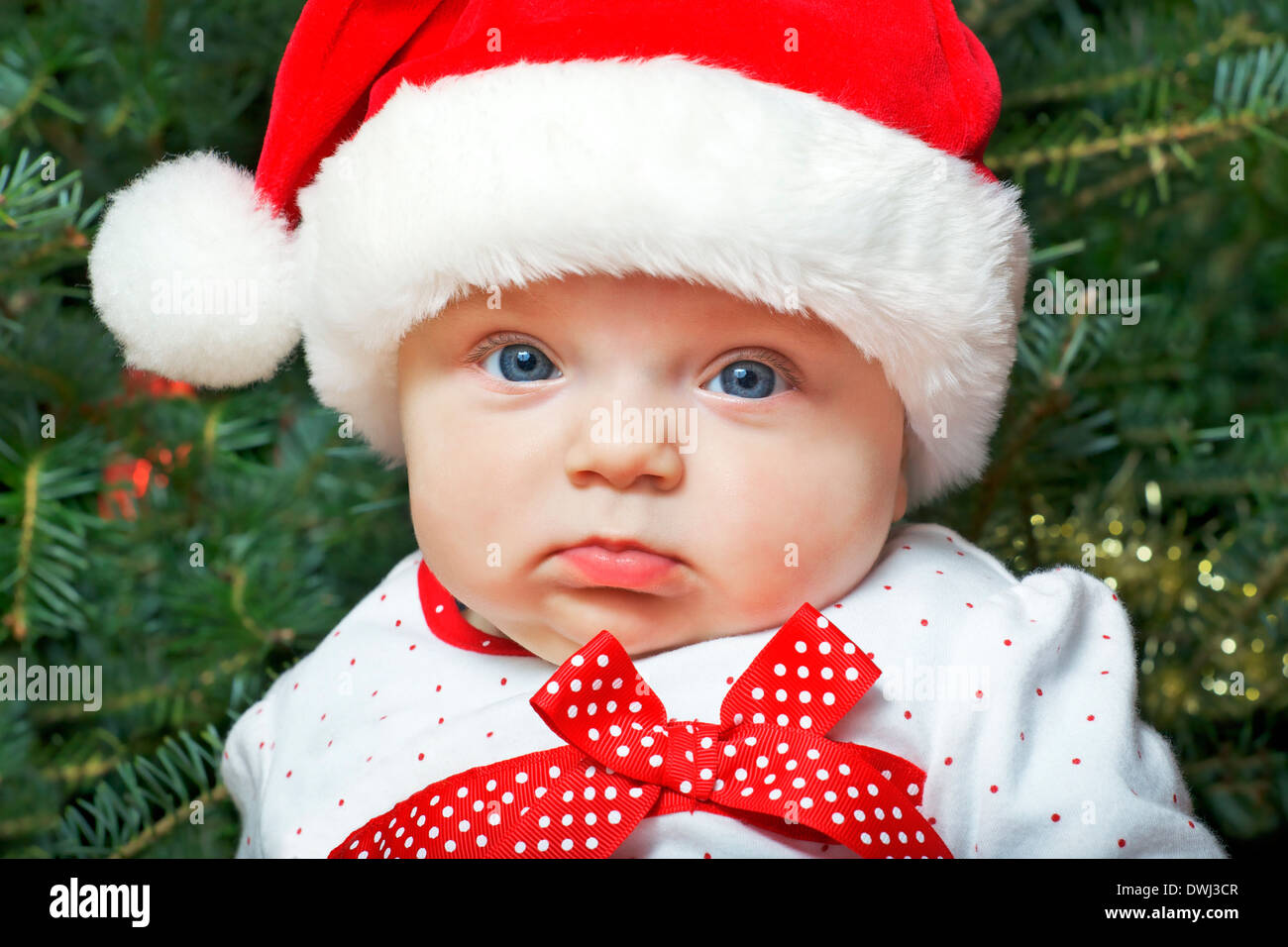 Baby girl wearing Santa Claus hat with Christmas tree in the backgroung Stock Photo