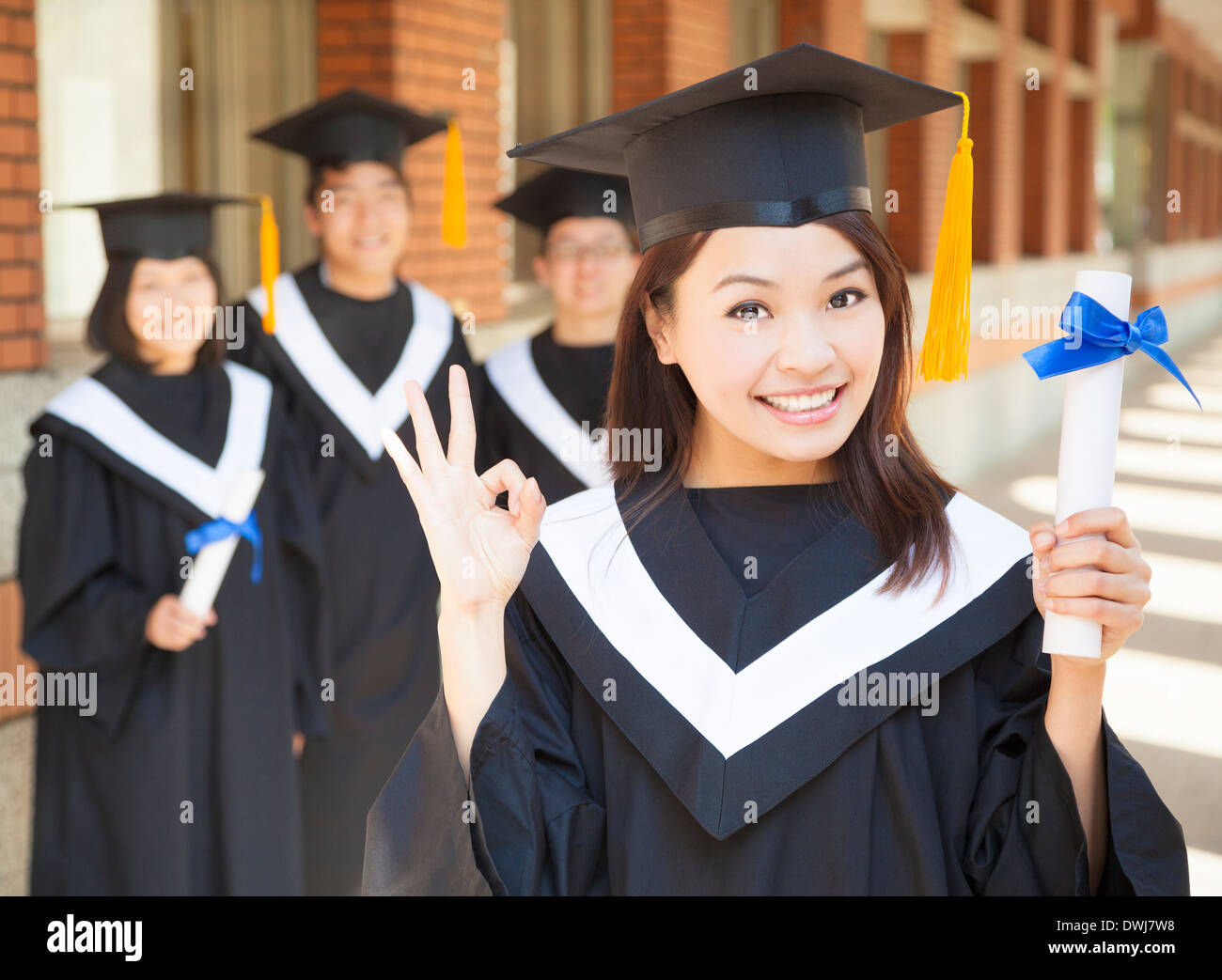 young college graduate holding diploma and make a gesture at campus Stock Photo