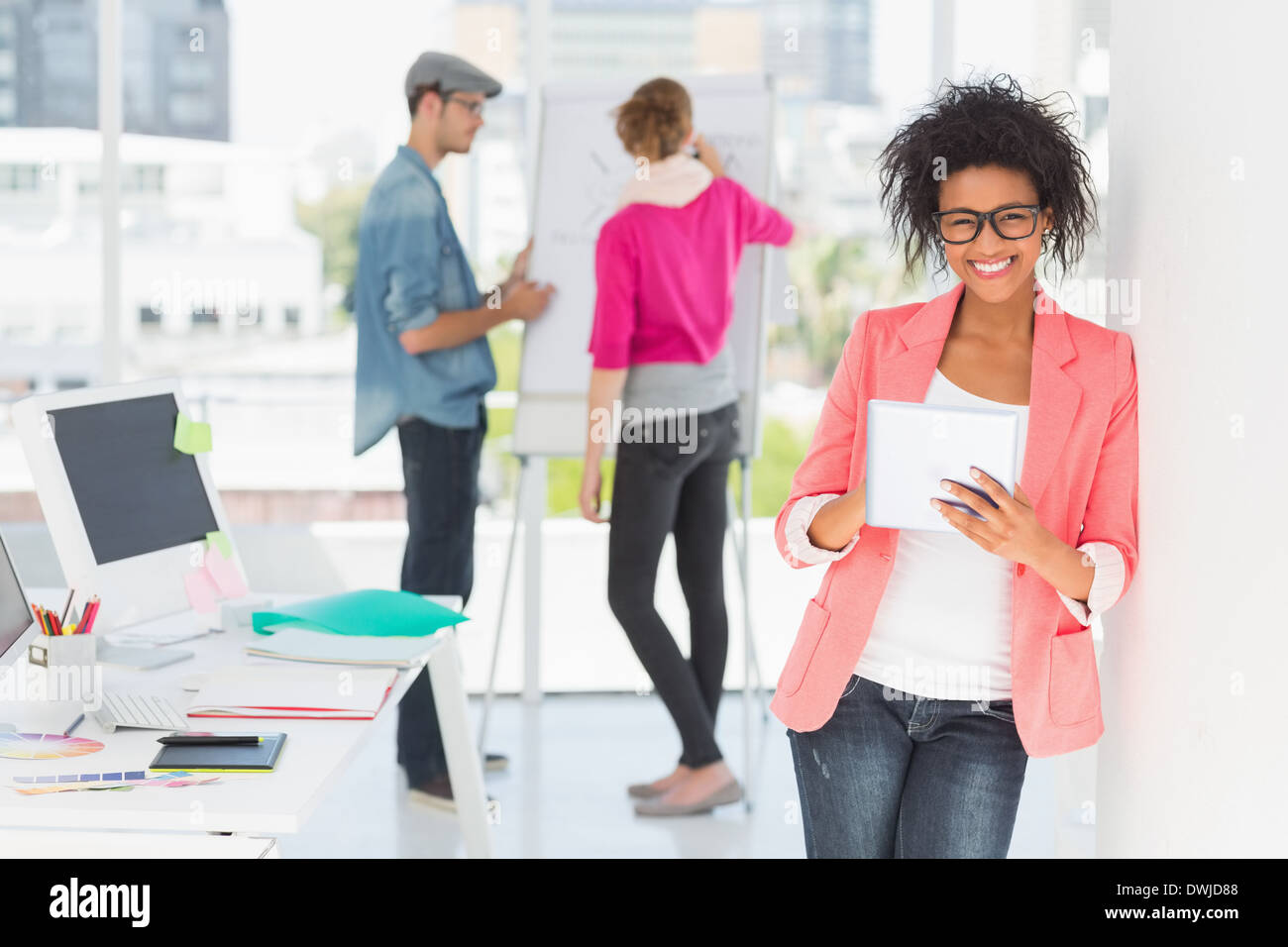 Artist using digital tablet with colleagues in background at office Stock Photo