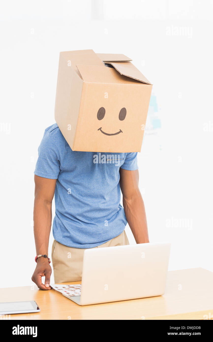 Man with happy smiley box over face in front of laptop Stock Photo