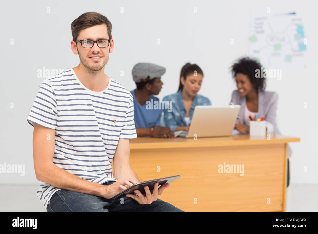 Artist using digital tablet with colleagues in background at office Stock Photo