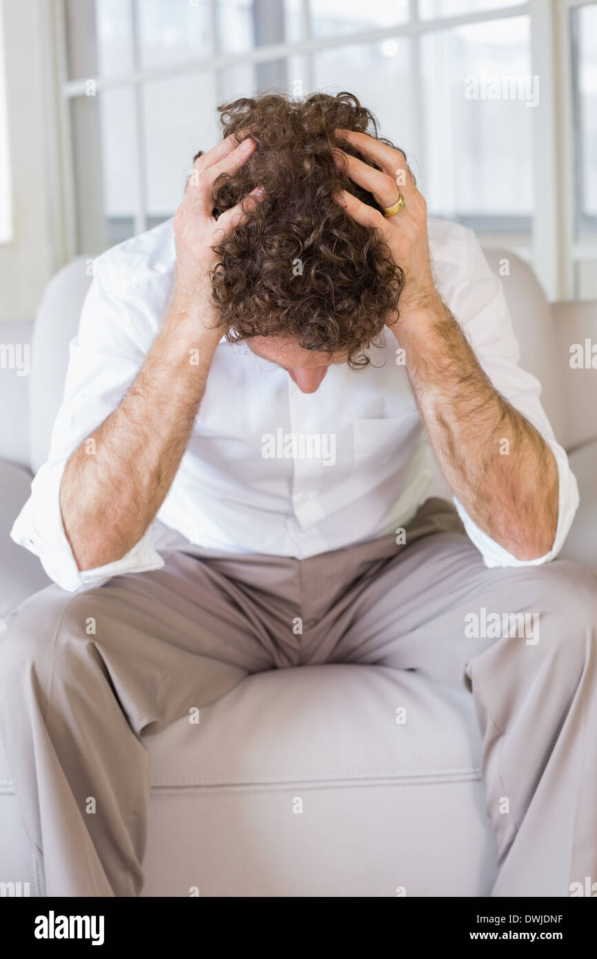 Well dressed man sitting with head in hands at home Stock Photo