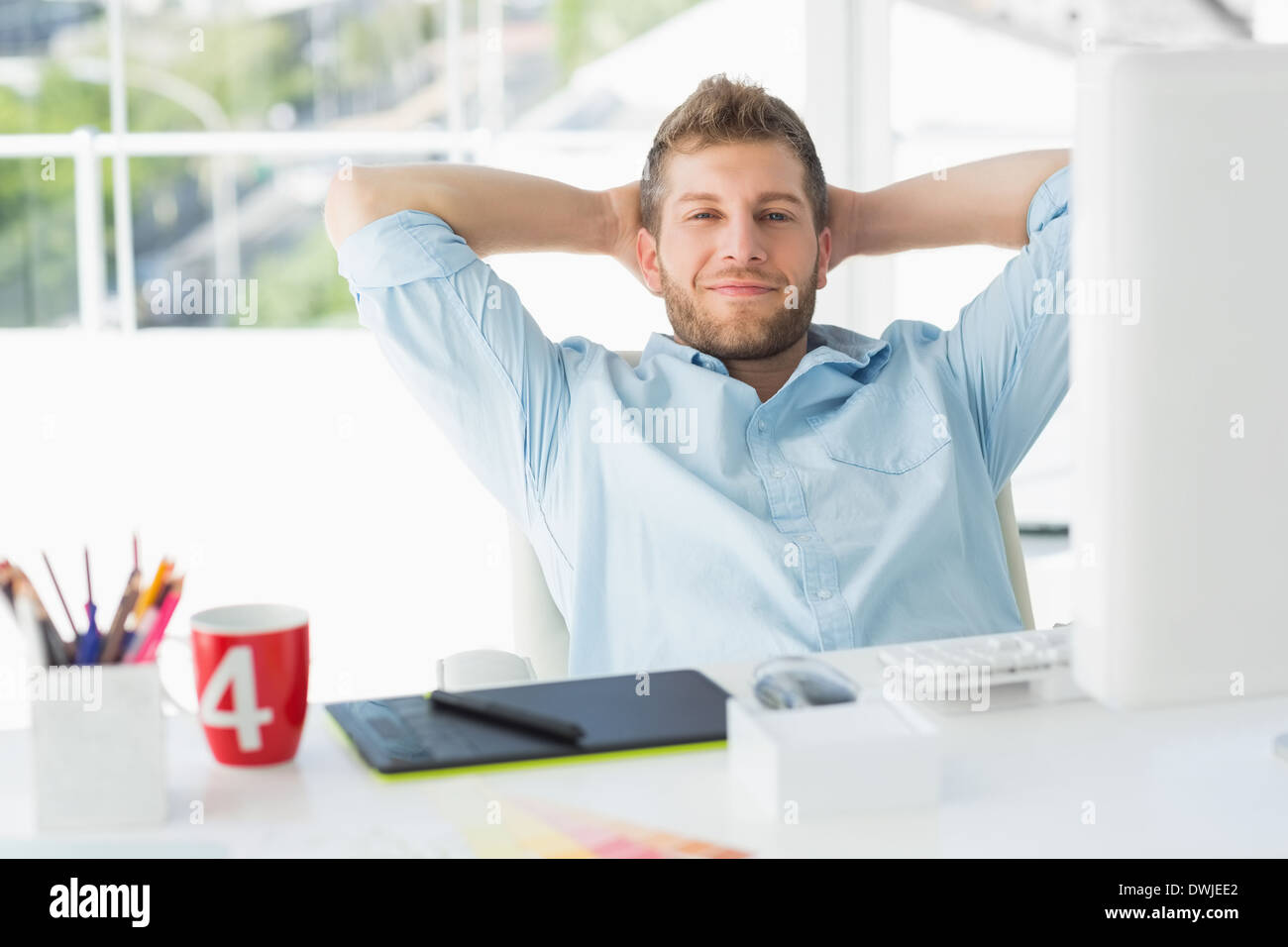 Designer relaxing at his desk smiling at camera Stock Photo - Alamy