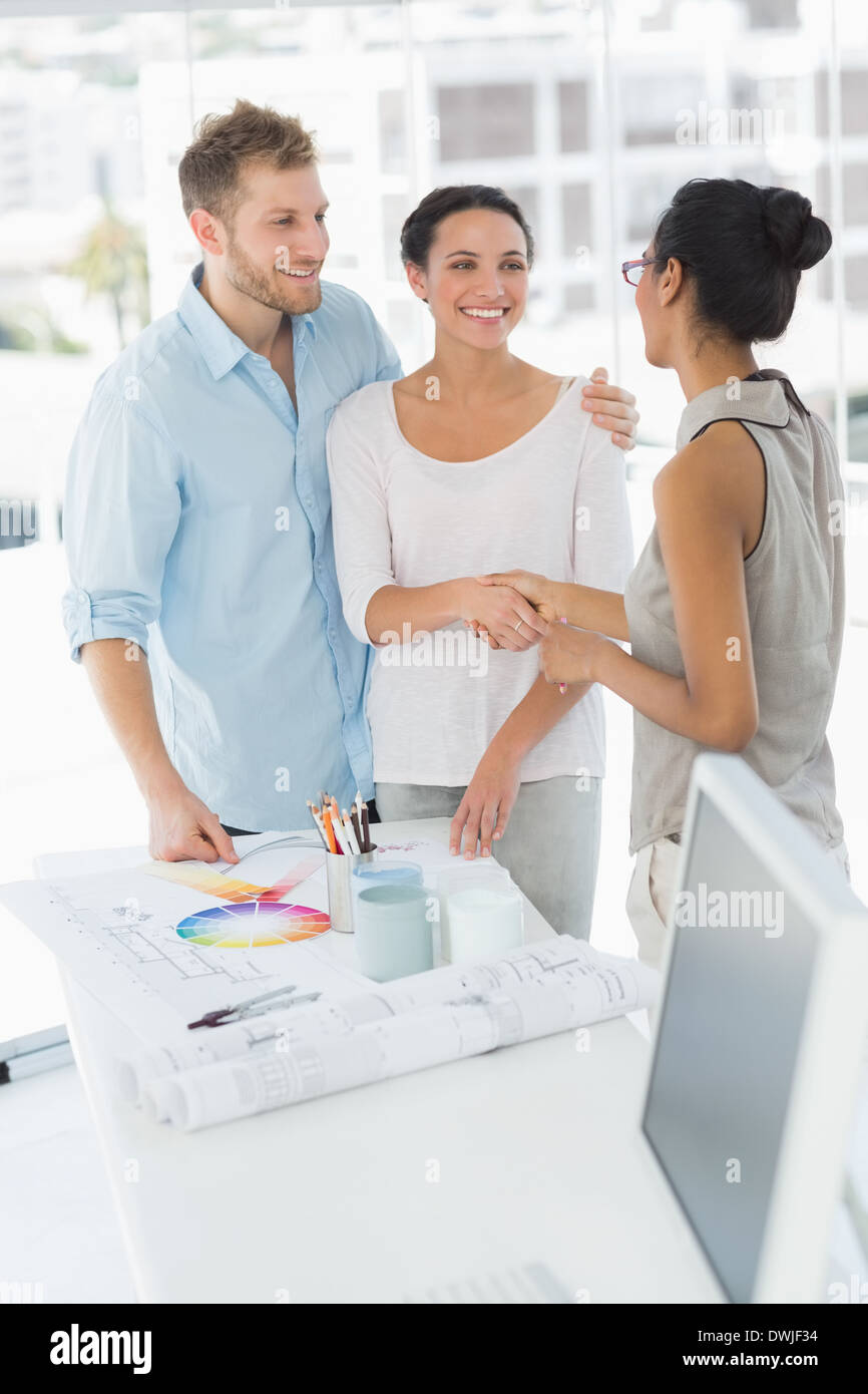 Interior designer shaking hands with smiling client Stock Photo - Alamy