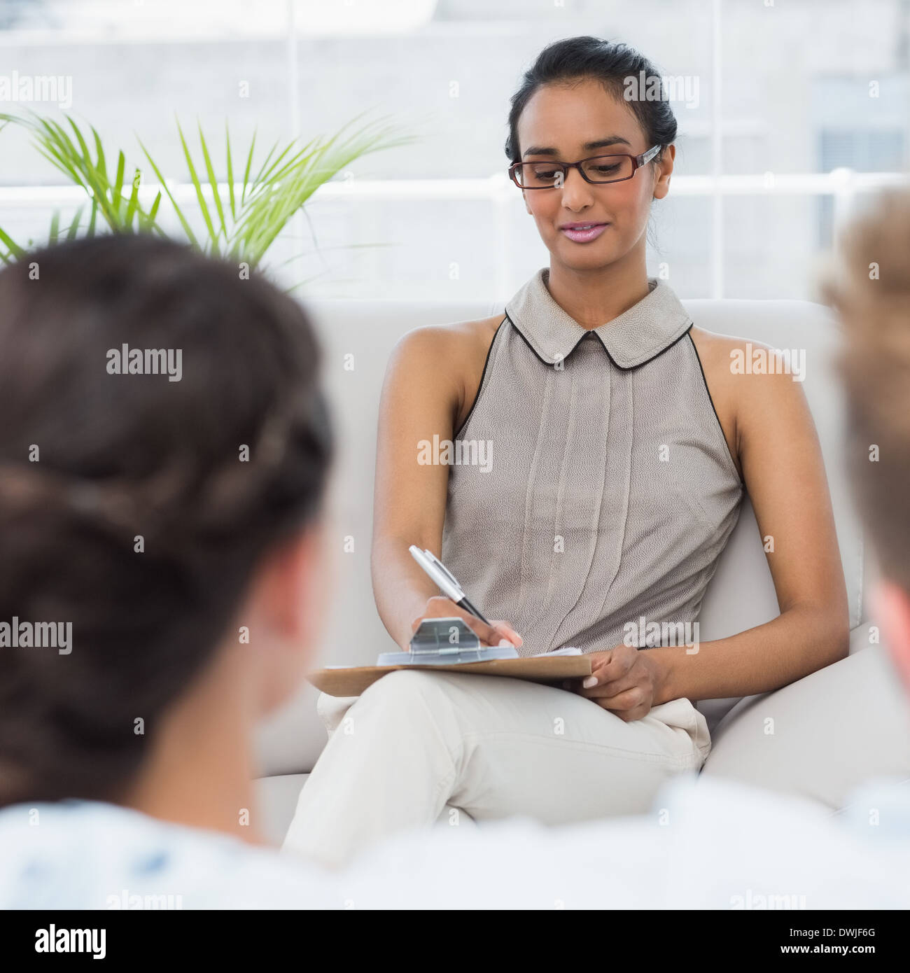 Therapist talking with couple on the couch and taking notes Stock Photo