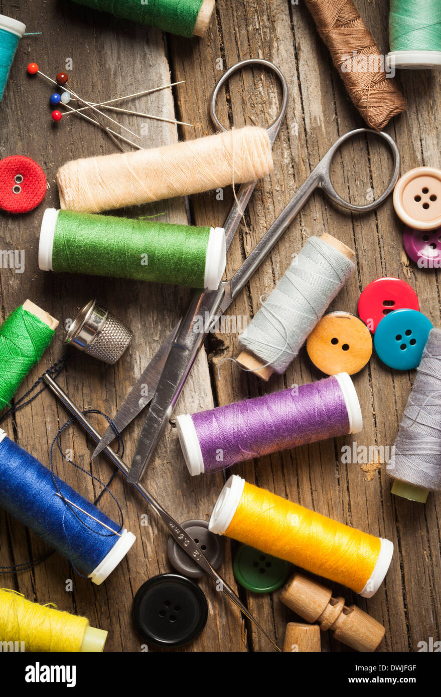 Scattered sewing spools and buttons, scissors and needles Stock Photo