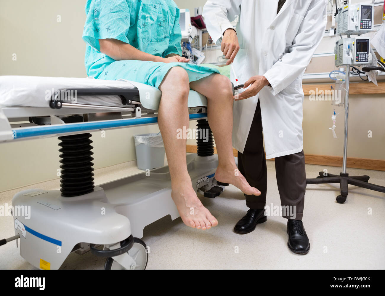 Neurologist Examining Patient's Knee With Hammer In Hospital Stock Photo