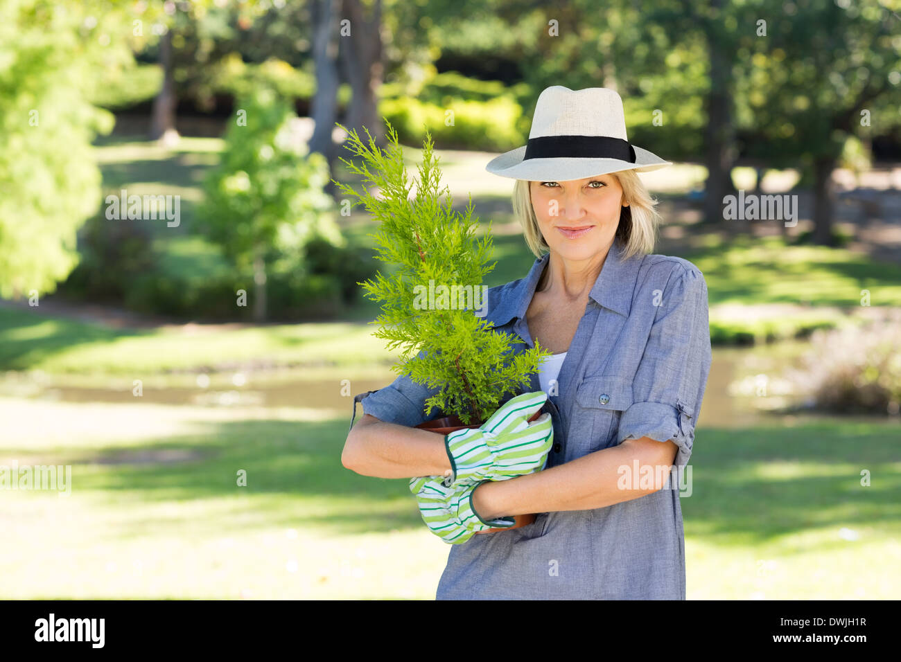 Woman holding pot plant in garden Stock Photo - Alamy