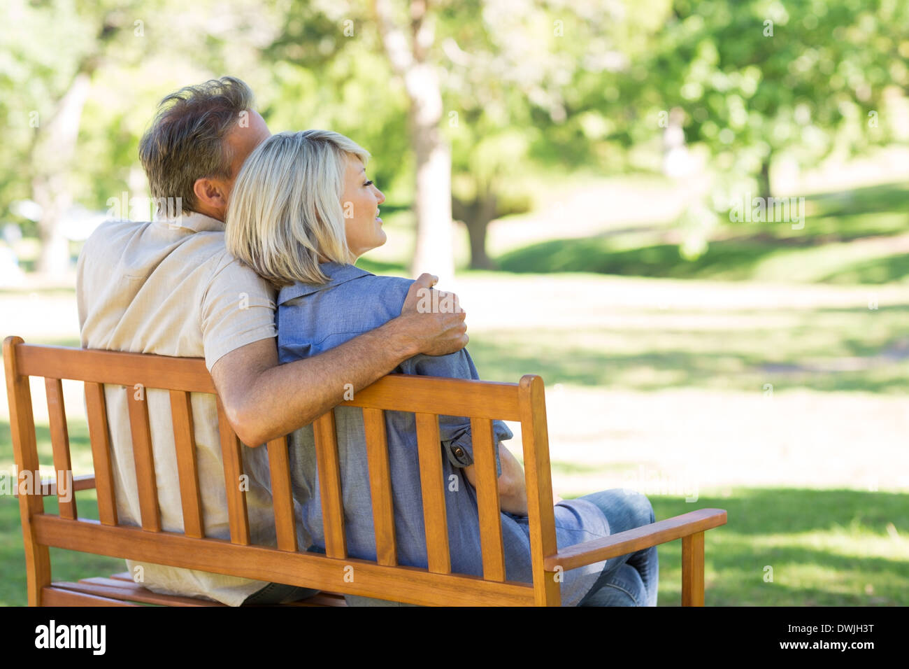 Couple sitting on park bench Stock Photo - Alamy