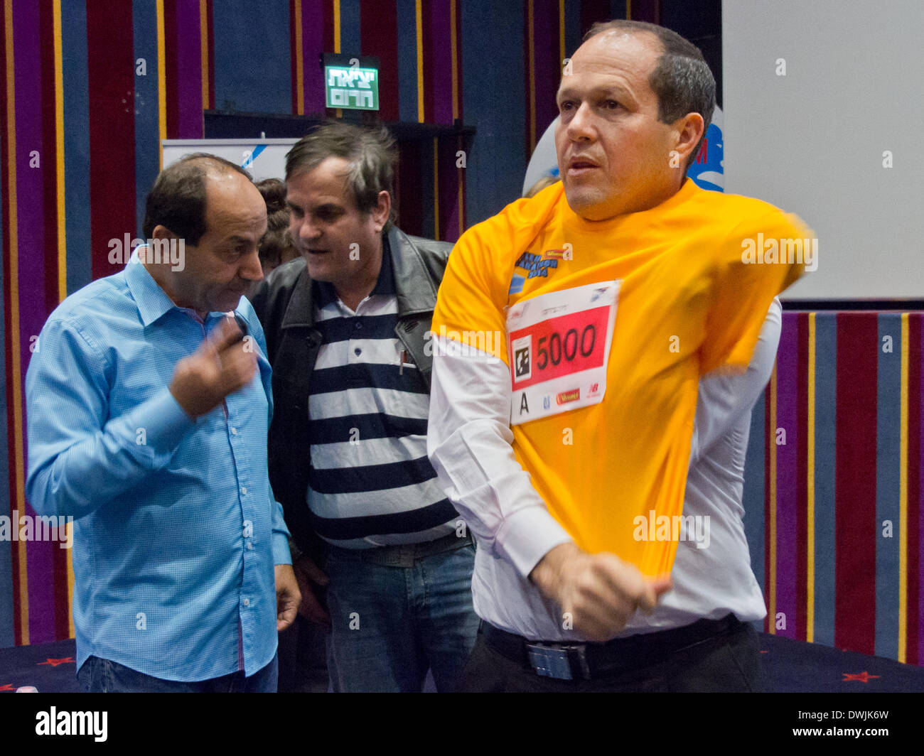 Jerusalem, Israel. 10th March, 2014. Jerusalem Mayor NIR BARKAT tries on the official Jerusalem 2014 International Marathon t-shirt personalized with his runner number after announcing the marathon set to take place March 21st with the expected participation of more than 25,000 runners including 2,446 registered from 54 countries. This will be the fourth marathon taking place in the city. Credit:  Nir Alon/Alamy Live News Stock Photo