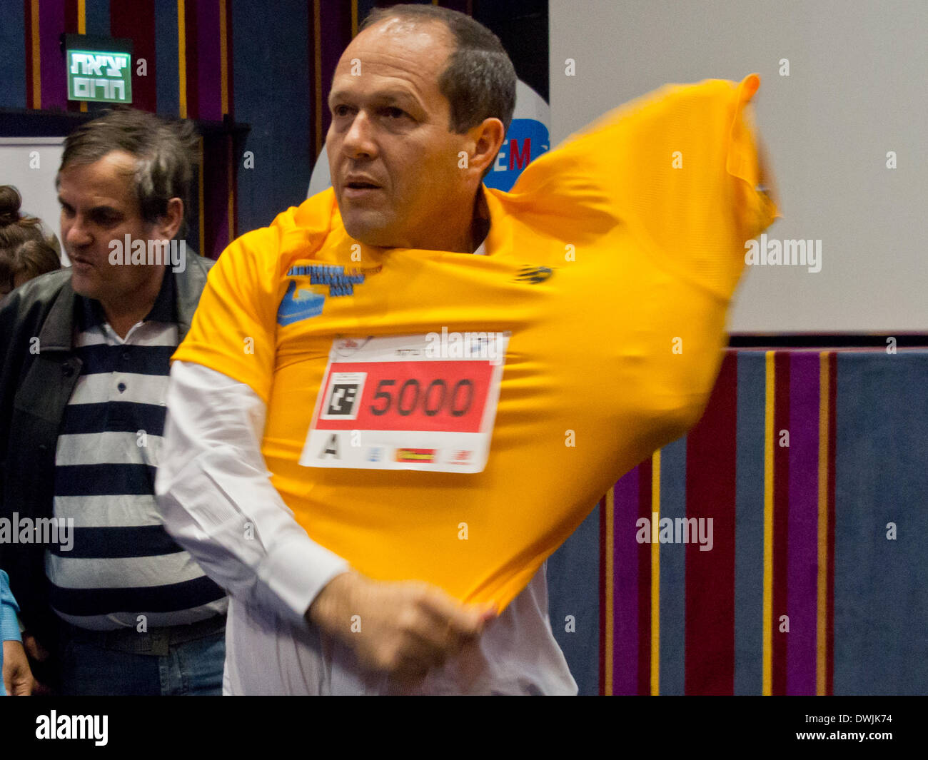 Jerusalem, Israel. 10th March, 2014. Jerusalem Mayor NIR BARKAT tries on the official Jerusalem 2014 International Marathon t-shirt personalized with his runner number after announcing the marathon set to take place March 21st with the expected participation of more than 25,000 runners including 2,446 registered from 54 countries. This will be the fourth marathon taking place in the city. Credit:  Nir Alon/Alamy Live News Stock Photo