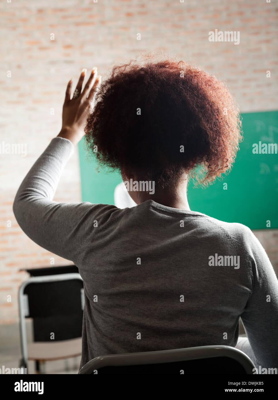 Female Student Raising Hand To Answer In Classroom Stock Photo