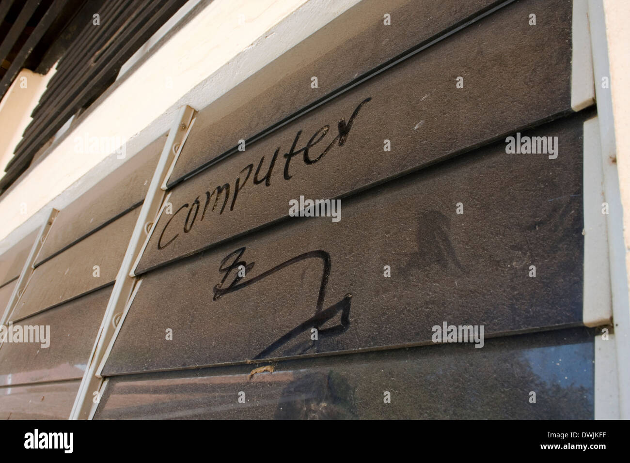 The word computer is written on a dusty louvered glass window at the University of Agriculture in Kampong Cham, Cambodia. Stock Photo