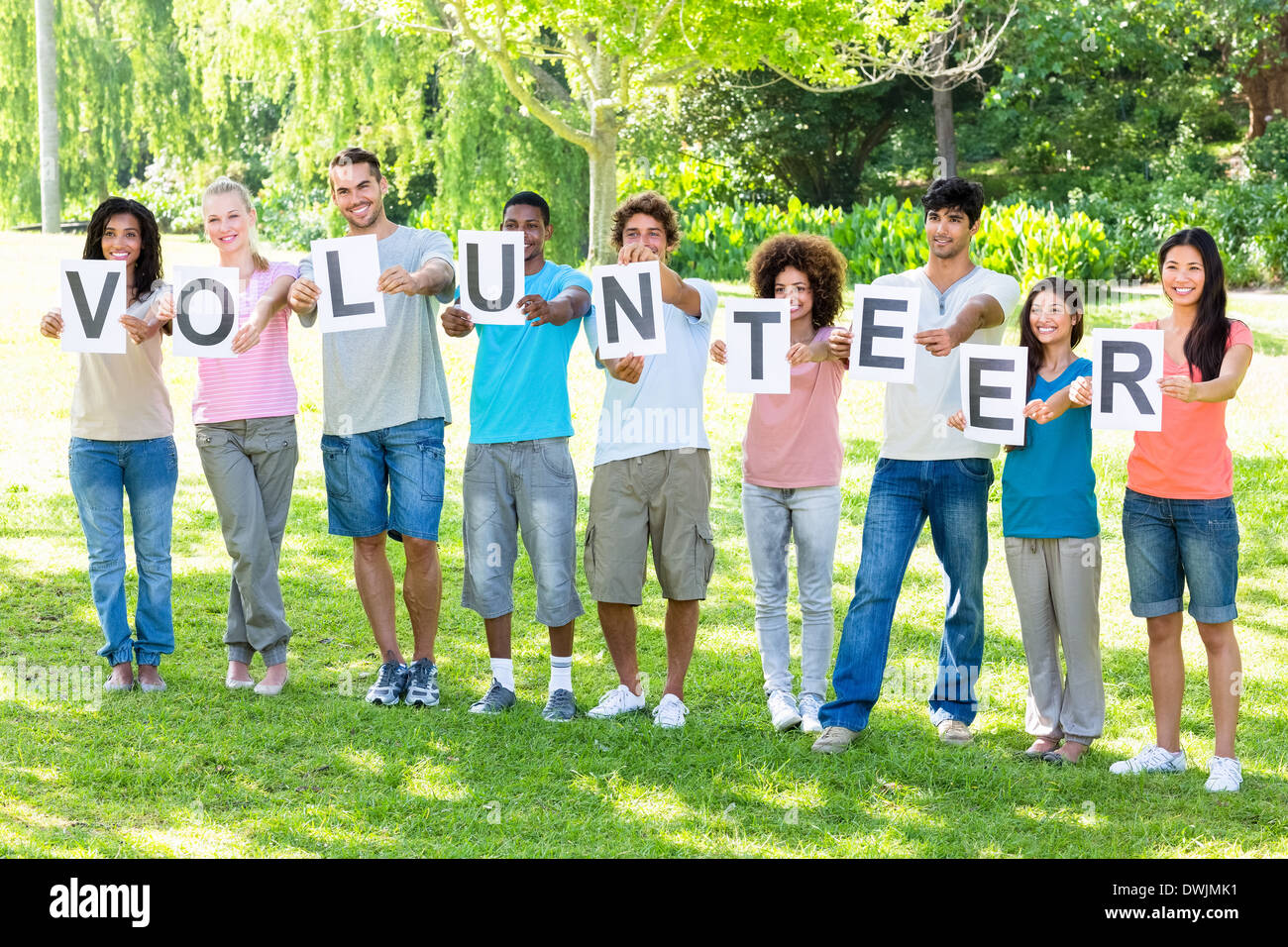 Friends holding placards spelling volunteer Stock Photo Alamy