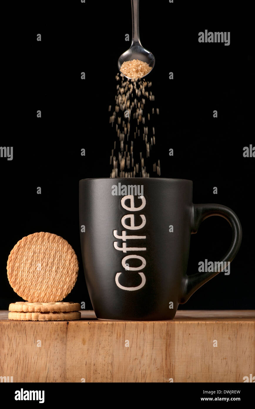 adding sugar to a mug of coffee Stock Photo