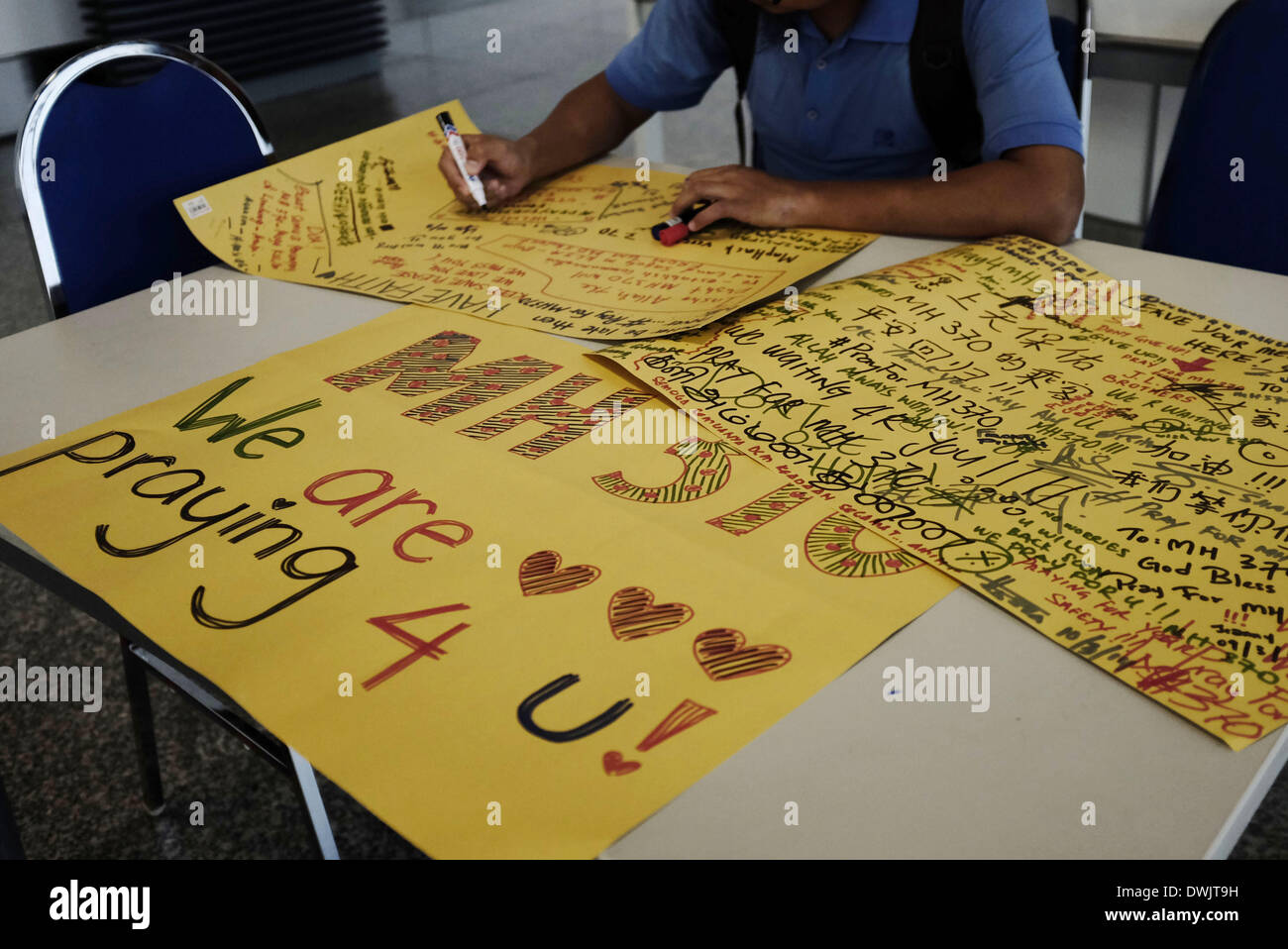 Sepang, SELANGOR, MALAYSIA. 10th Mar, 2014. A man writes a wishing message on a cardboard at Kuala Lumpur International Airport in Sepang. Investigative teams continue to search for the missing Malaysia Airlines flight MH370 and the 293 passengers that were travelling from Kuala Lumpur to Beijing. The airliner was reported missing on March 8, after it failed to check in as scheduled. © Kamal Sellehuddin/ZUMAPRESS.com/Alamy Live News Stock Photo