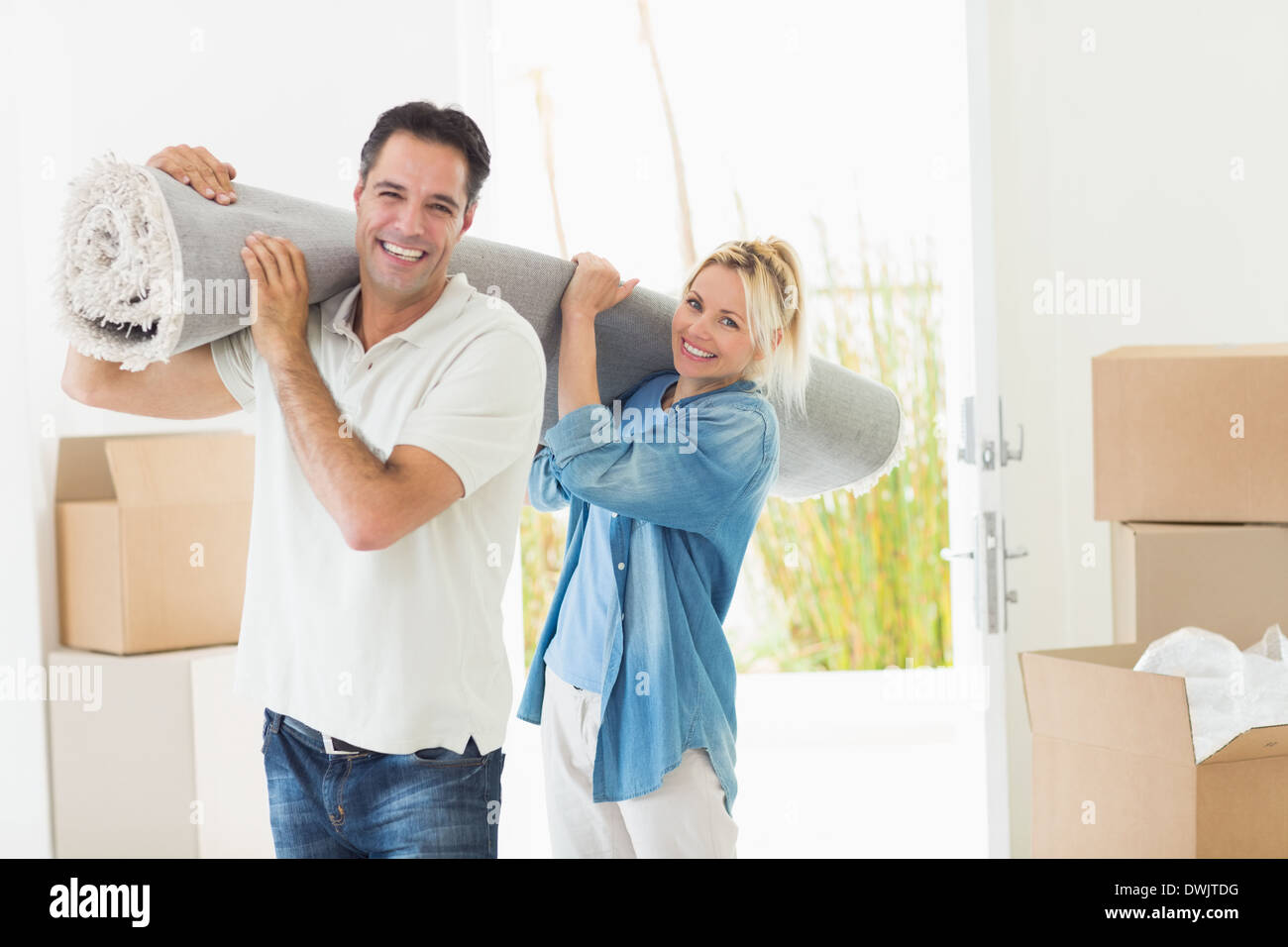Couple carrying rolled rug after moving in a house Stock Photo